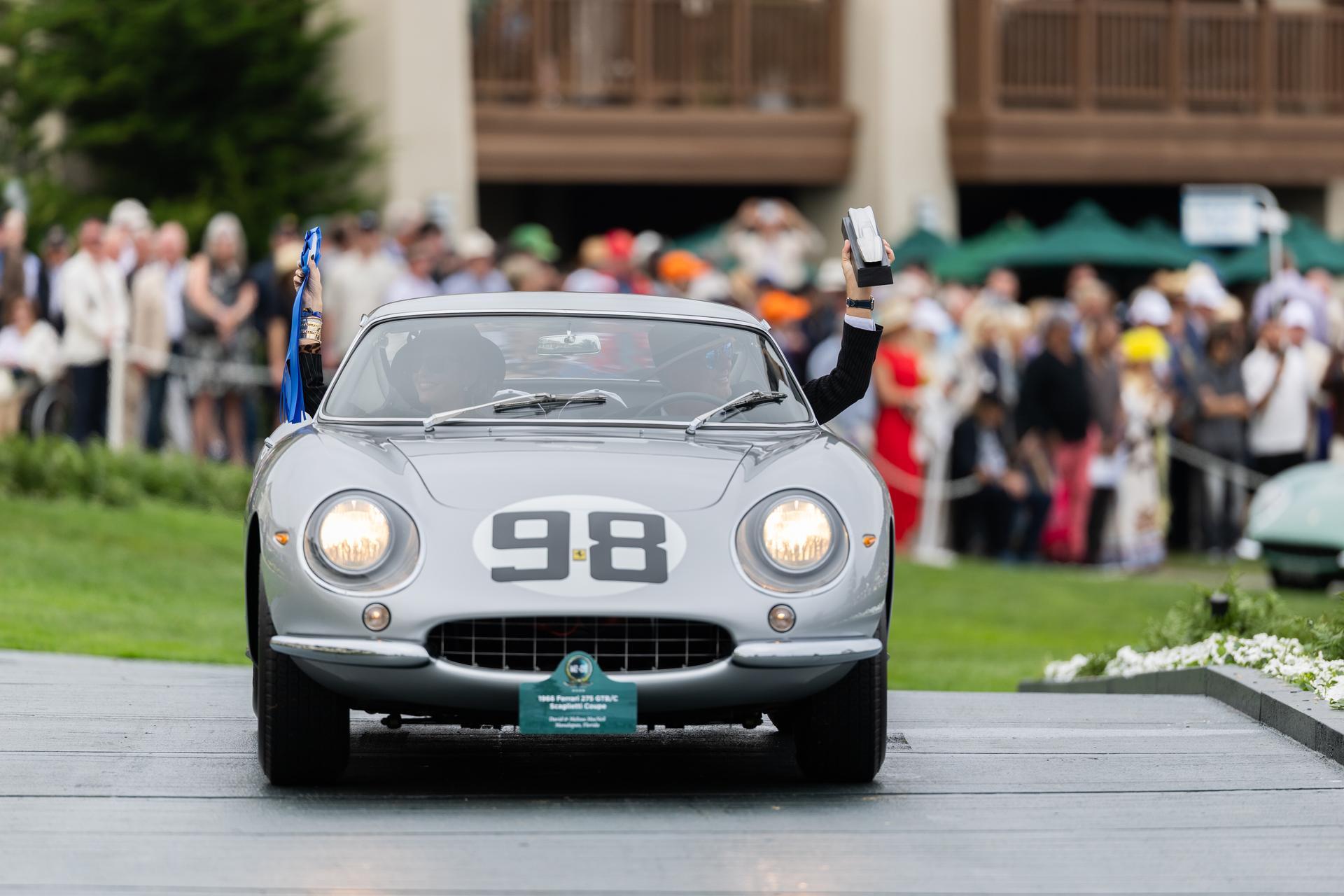 Silver 1966 Ferrari 275 GTB C Scaglietti Coupe with number 98 roundel collecting its trophy at Pebble Beach