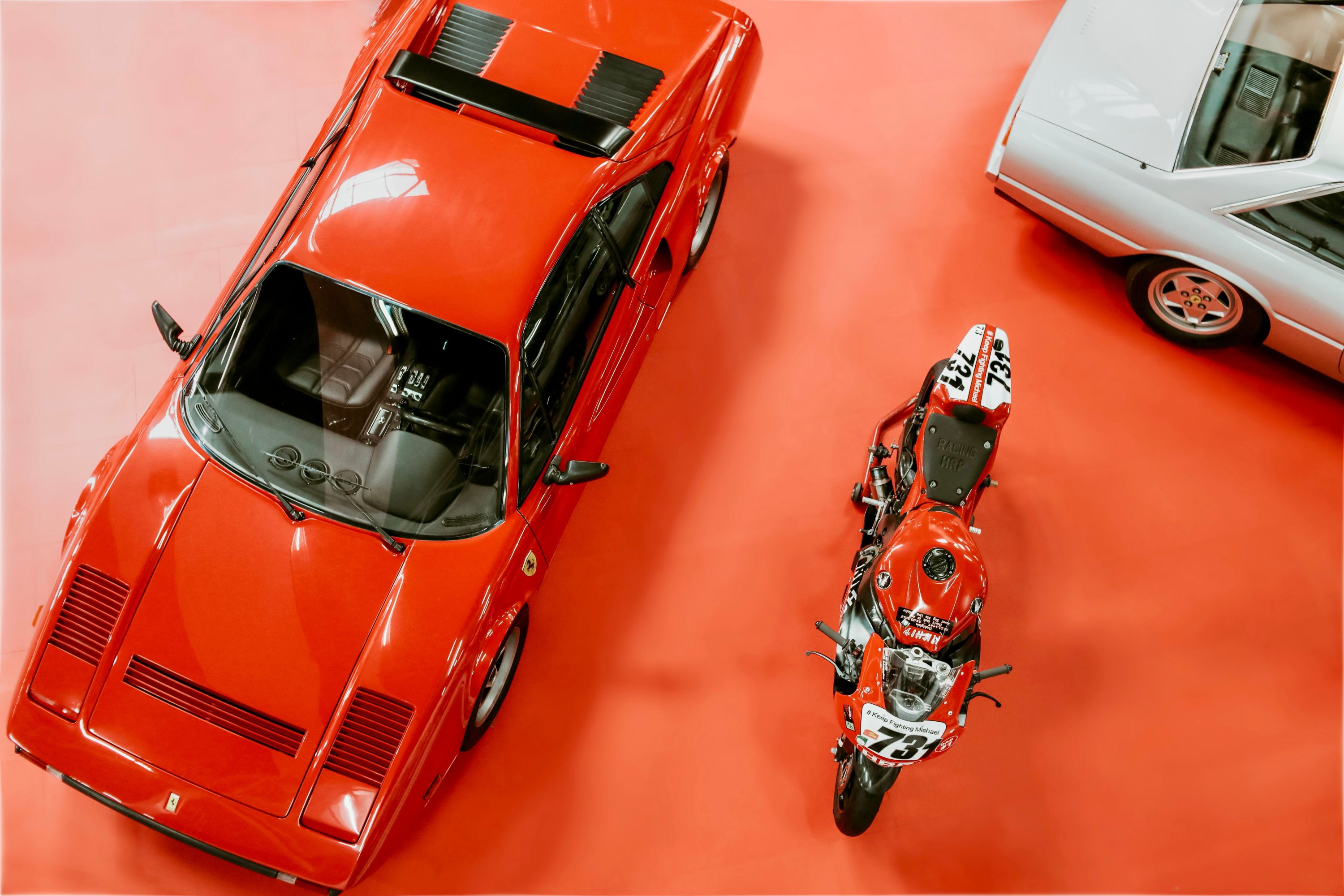 Classic Ferrari and a vintage motorcycle displayed at an automotive exhibition