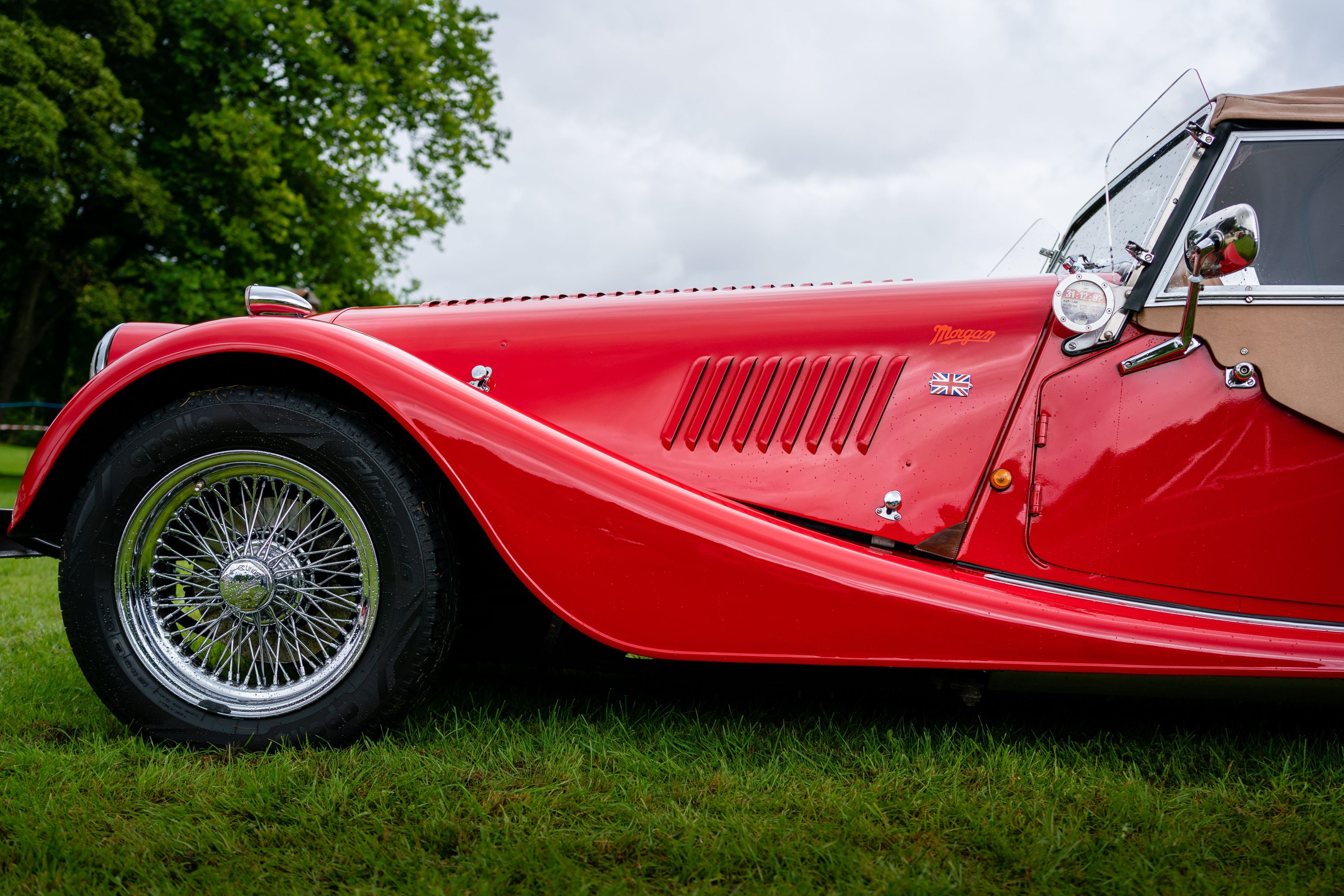 Side view of a red vintage Morgan sports car with a British flag emblem