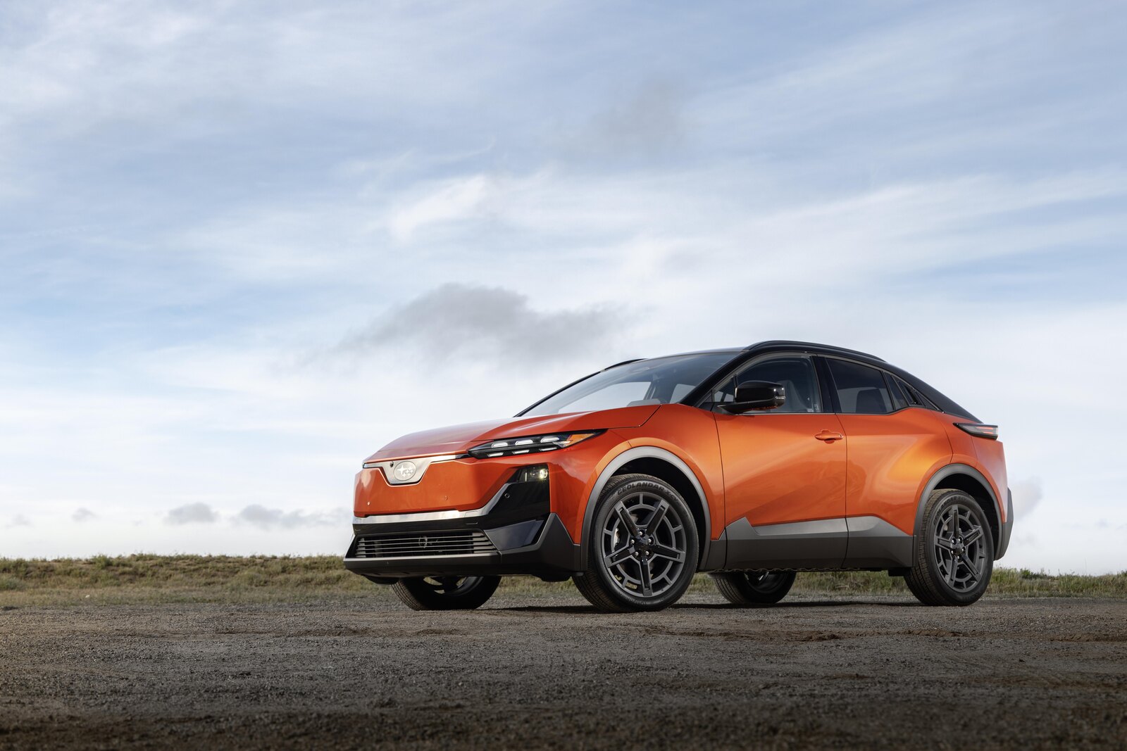 2026 Subaru Uncharted electric SUV in orange, front three-quarter view on a hilltop