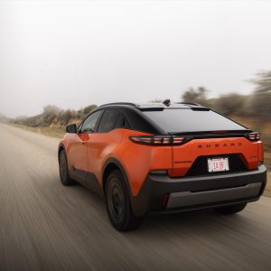 2026 Subaru Uncharted electric SUV in orange, rear three-quarter view on a gravel road