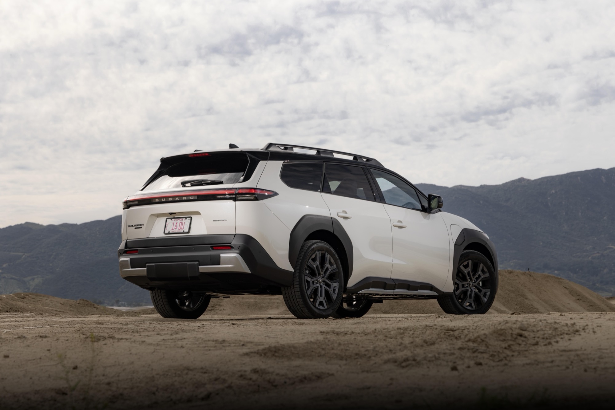 2026 Subaru Trailseeker in white, rear three-quarter view on a dirt road showing its roof rails