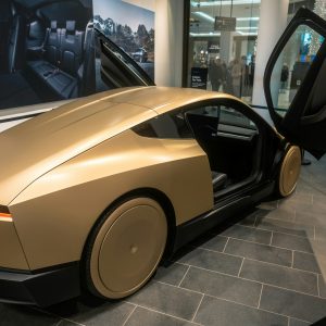 Gold Tesla Cybercab display prototype with its butterfly door raised, showing the two-seat cabin with no steering wheel, at the Tesla store in the Mall of Berlin