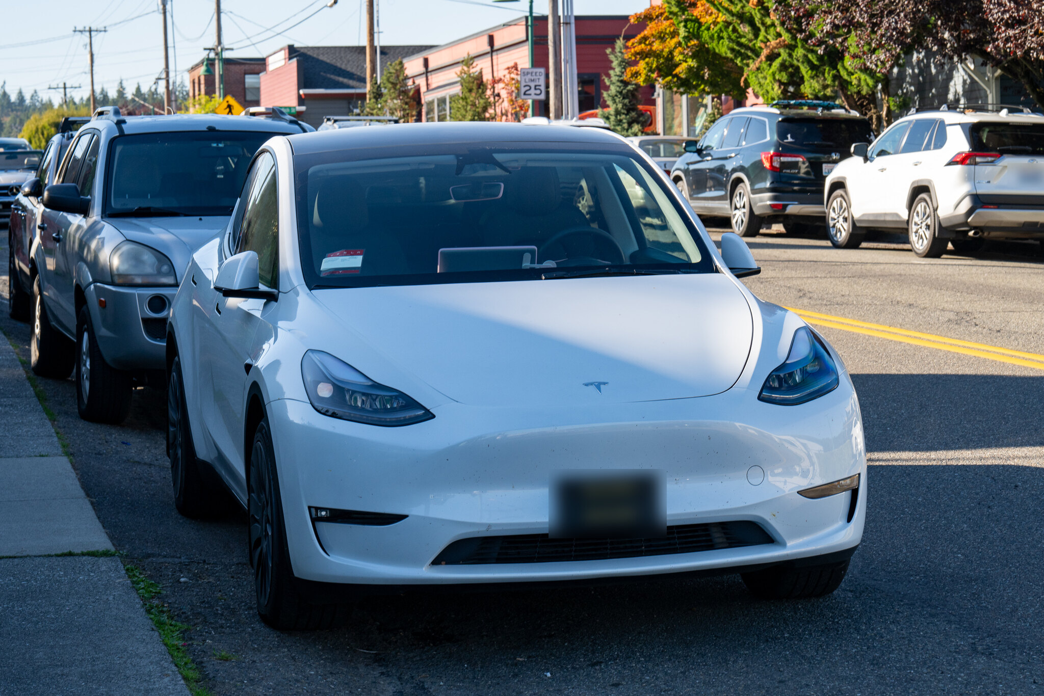 White 2023 Tesla Model Y parked at the curb on a downtown street in Gig Harbor, Washington