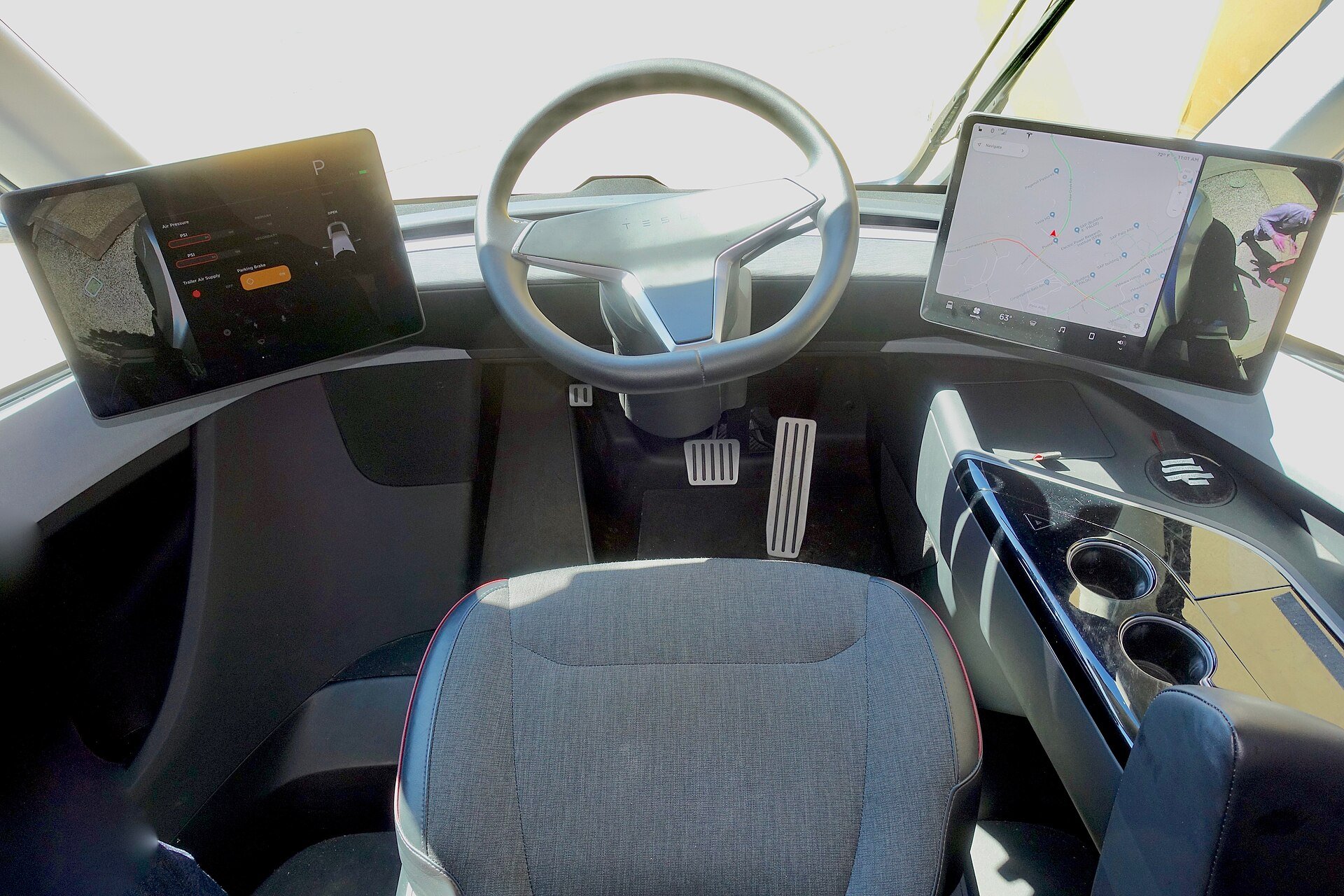 Driver's seat of a Tesla Semi prototype cab, centered behind the steering wheel with a touchscreen on each side