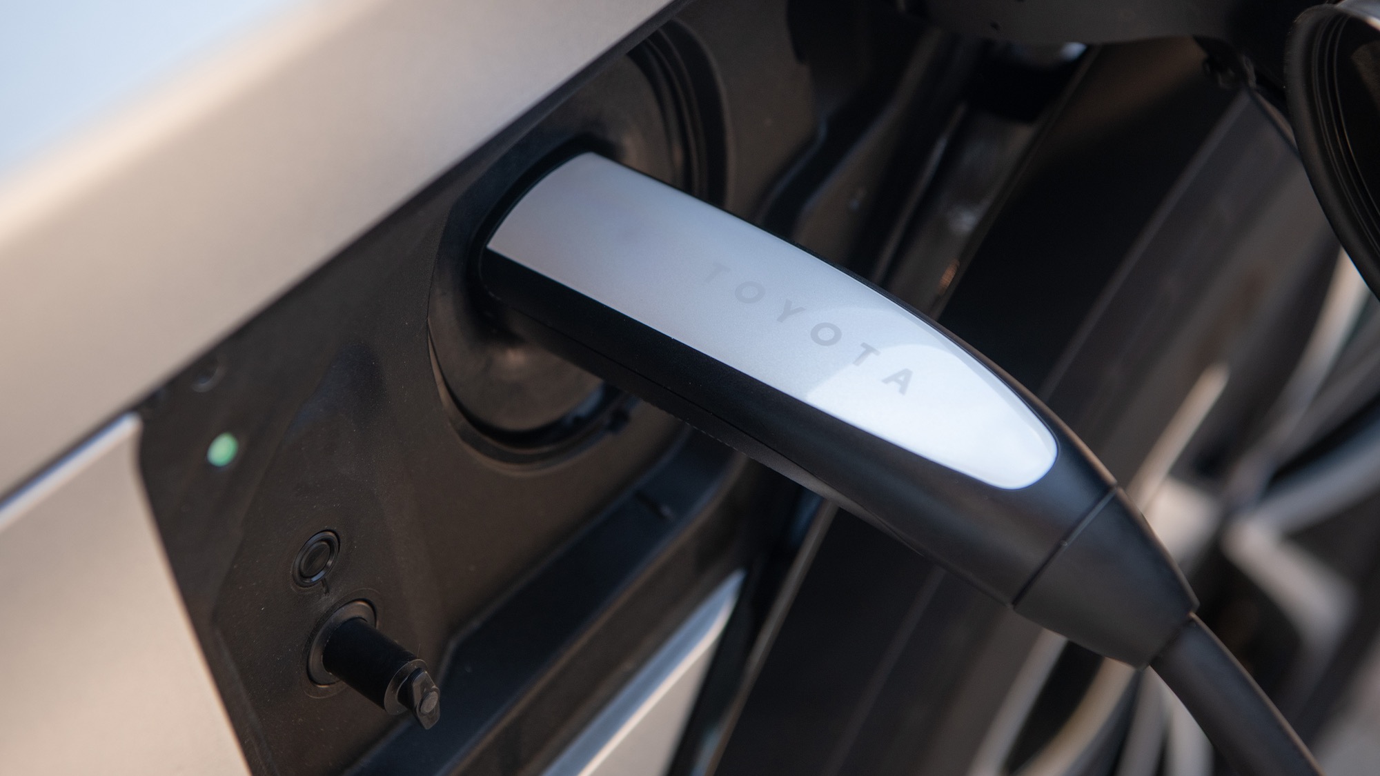 Close-up of a NACS charging connector plugged into the charge port of a 2026 Toyota bZ