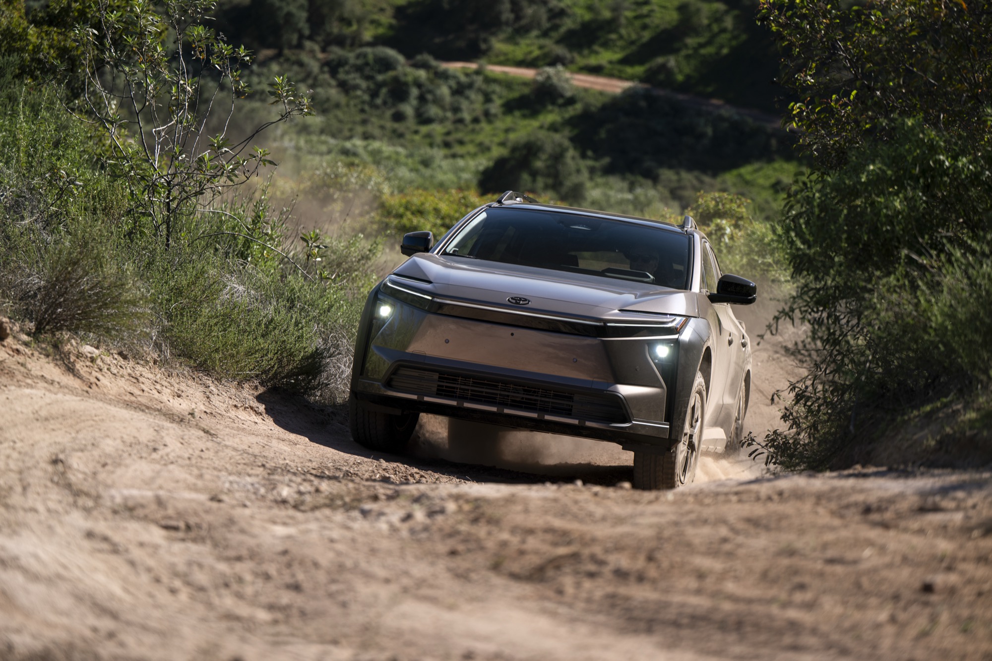 2026 Toyota bZ Woodland driving on a dirt trail, kicking up dust