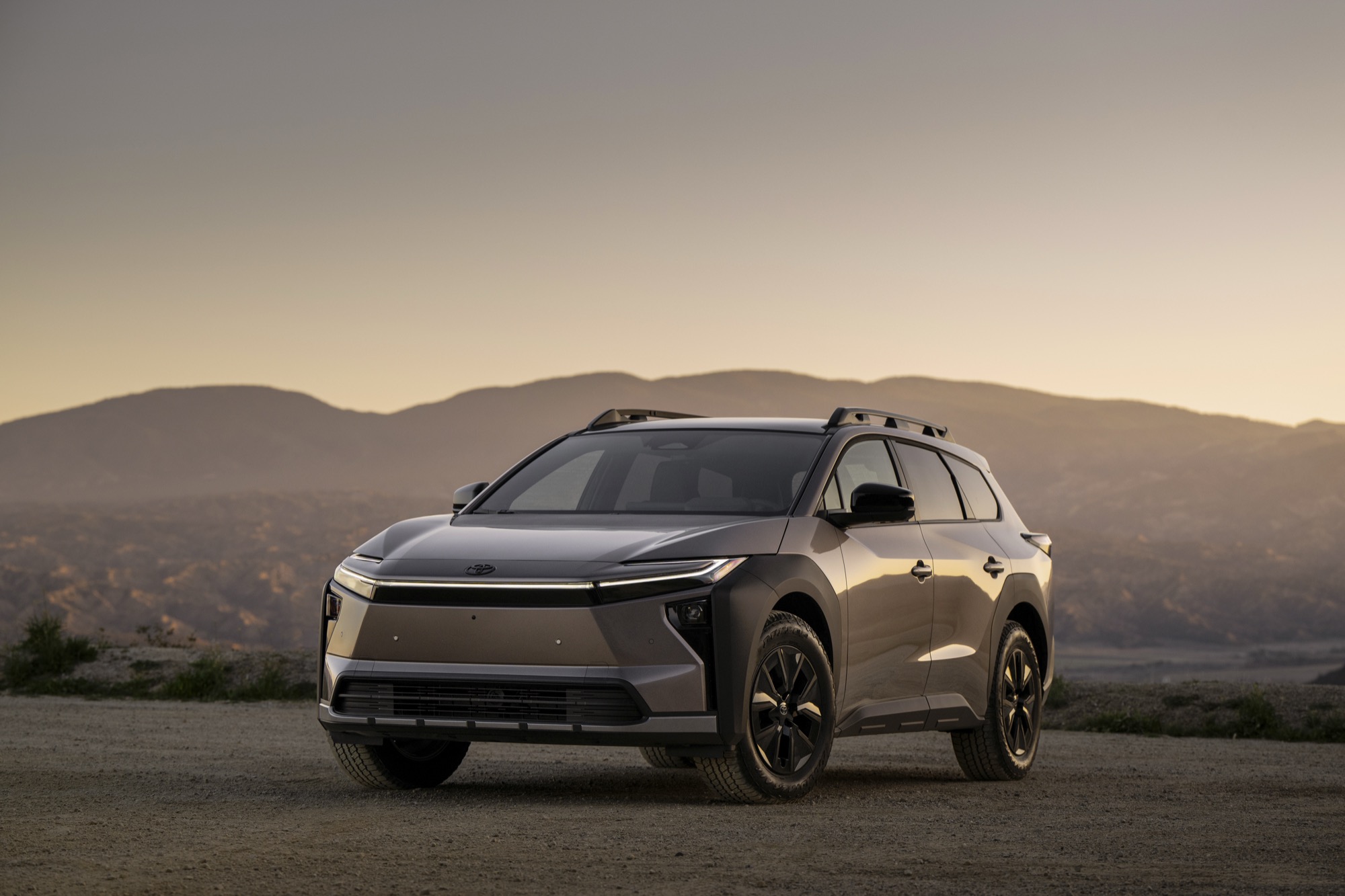 2026 Toyota bZ Woodland electric SUV in bronze with roof rails, front three-quarter view at sunset