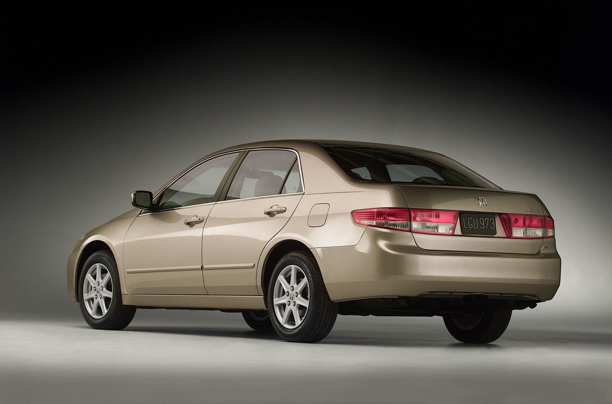 Rear three-quarter view of a gold 2004 Honda Accord EX V-6 sedan in a studio