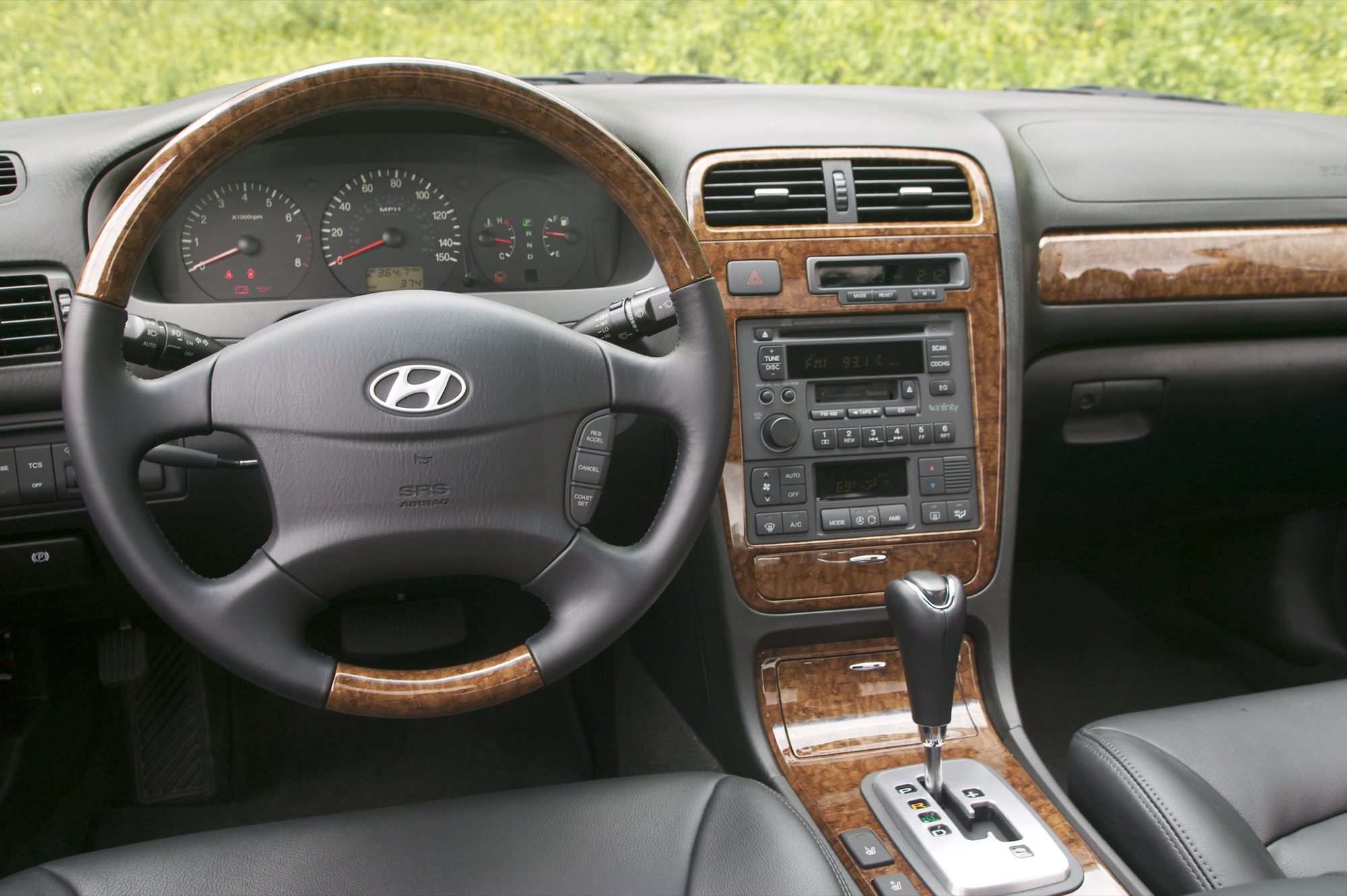 Dashboard of the 2004 Hyundai XG350 with wood-grain steering wheel, center stack trim and gray leather seats