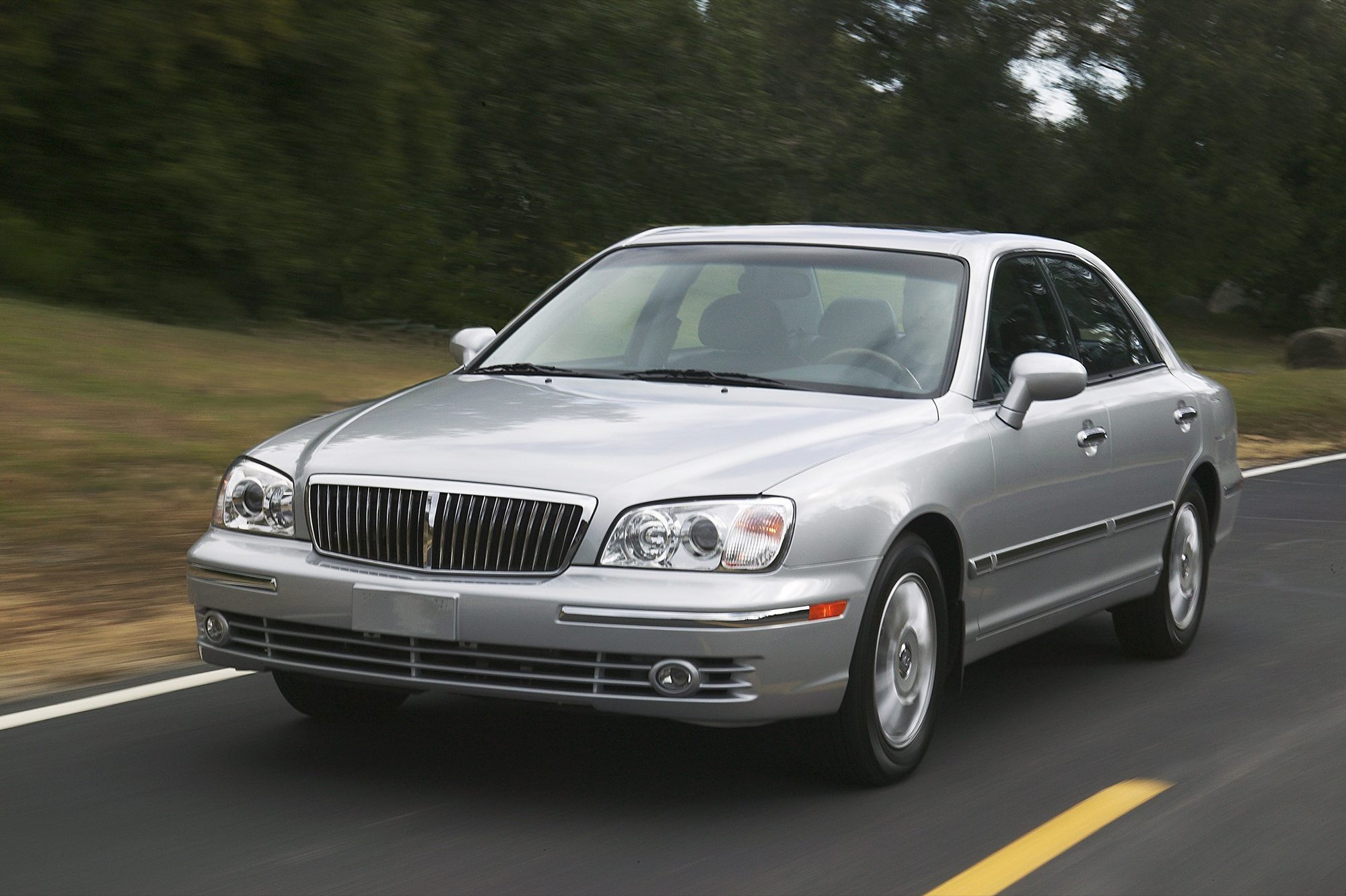 Silver 2004 Hyundai XG350 sedan driving on a two-lane road, front three-quarter view