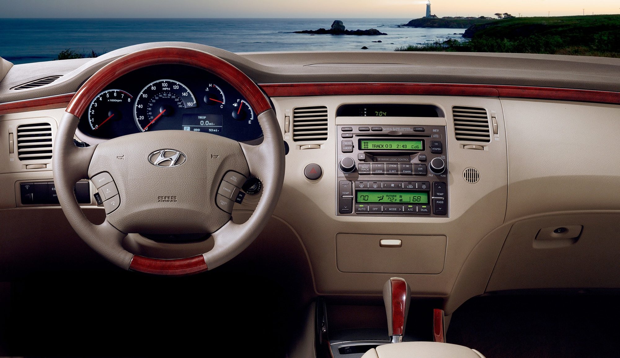 Dashboard of the 2006 Hyundai Azera with a wood-and-leather steering wheel, woodgrain trim and in-dash six-disc CD changer