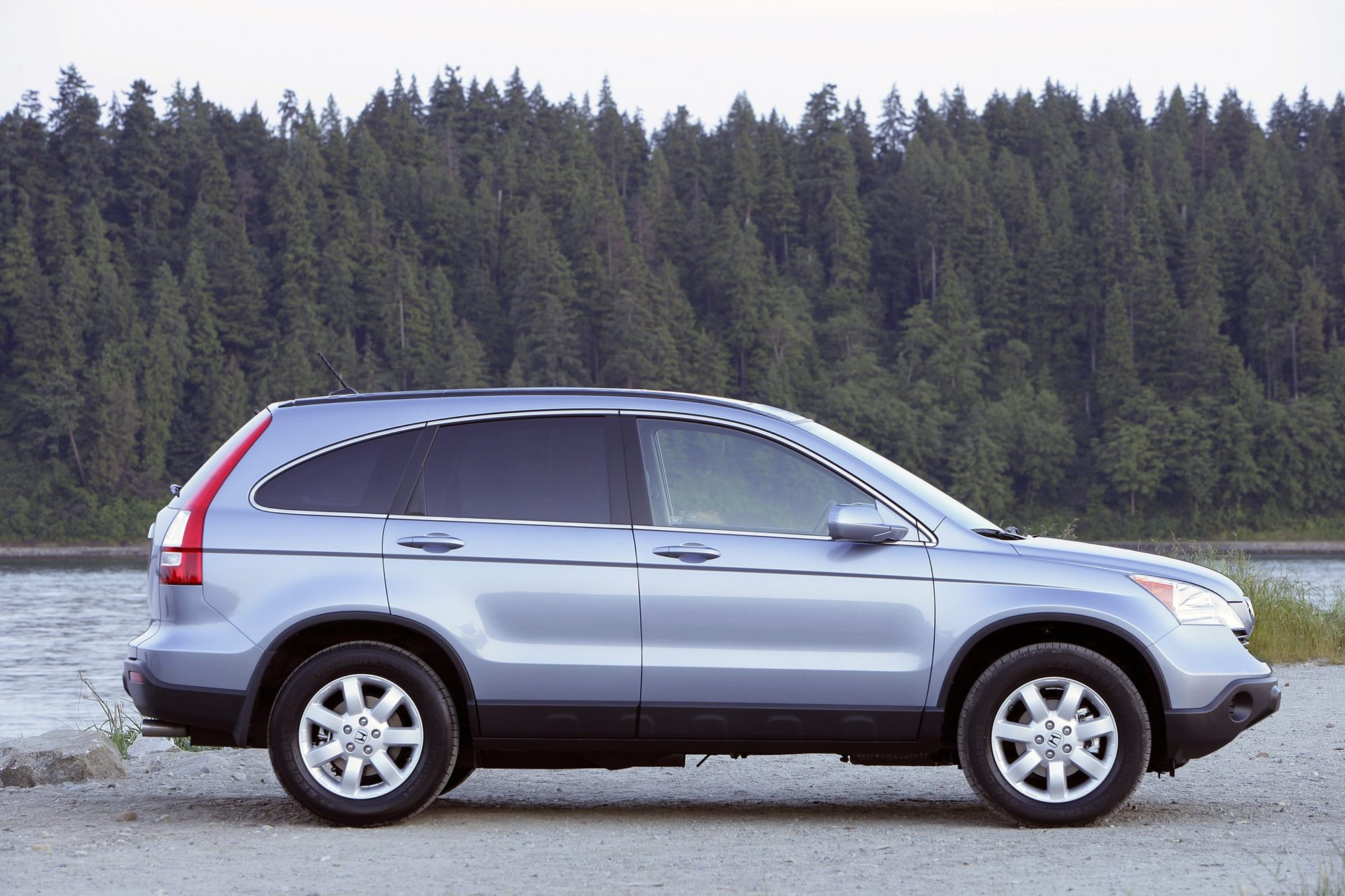 Light blue 2007 Honda CR-V EX-L in profile by a lake with evergreens
