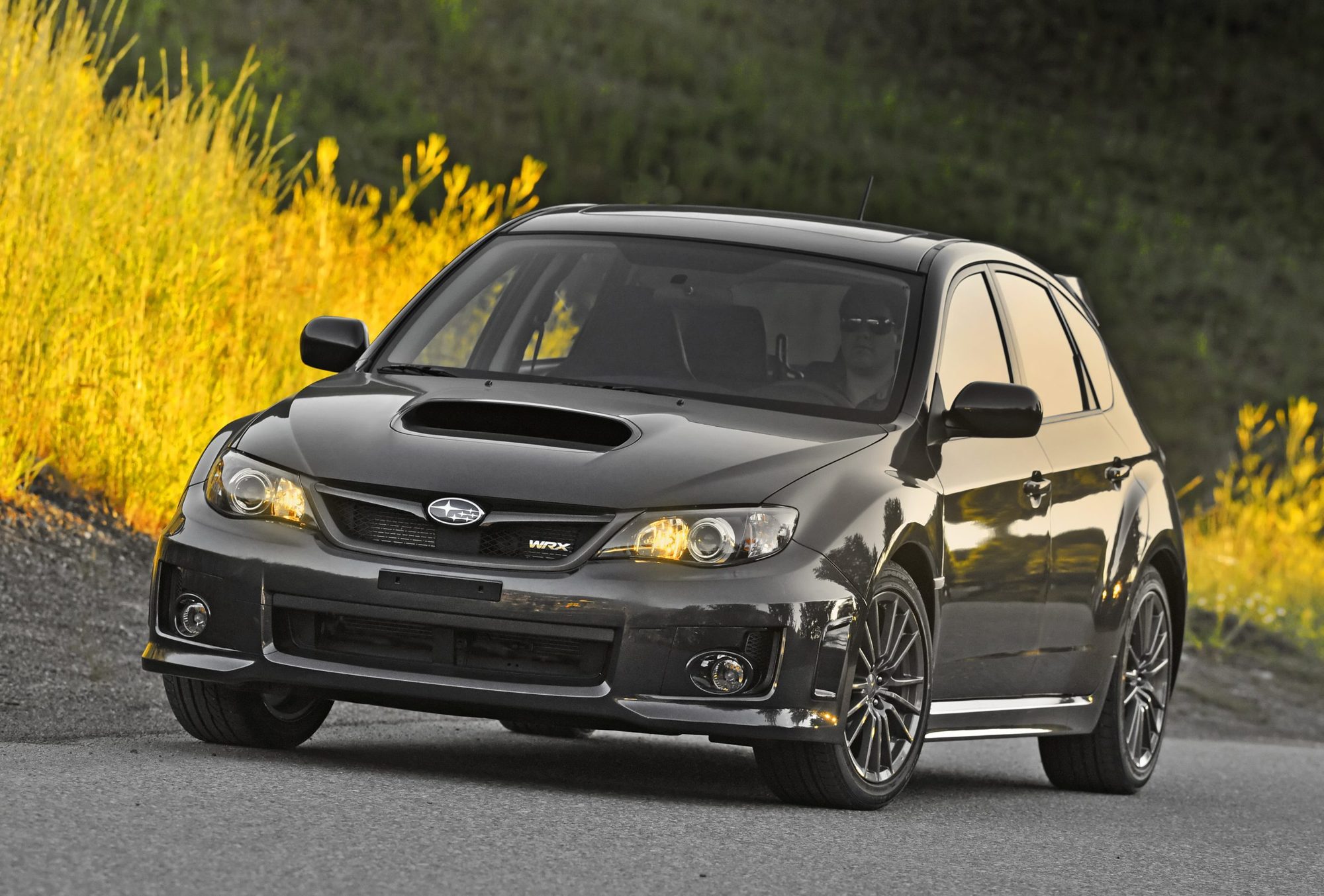 Dark gray 2011 Subaru Impreza WRX hatchback on a mountain road