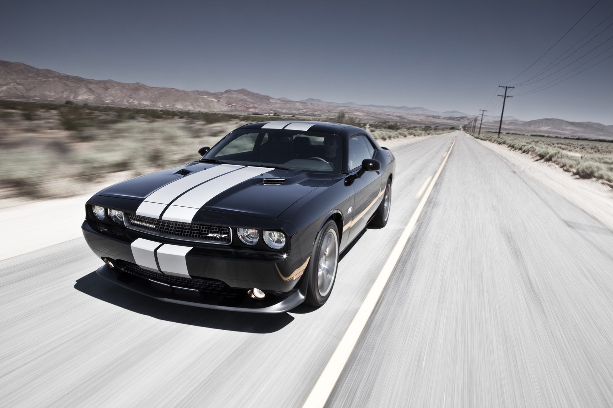 Black 2012 Dodge Challenger SRT8 392 with silver stripes driving on a desert highway