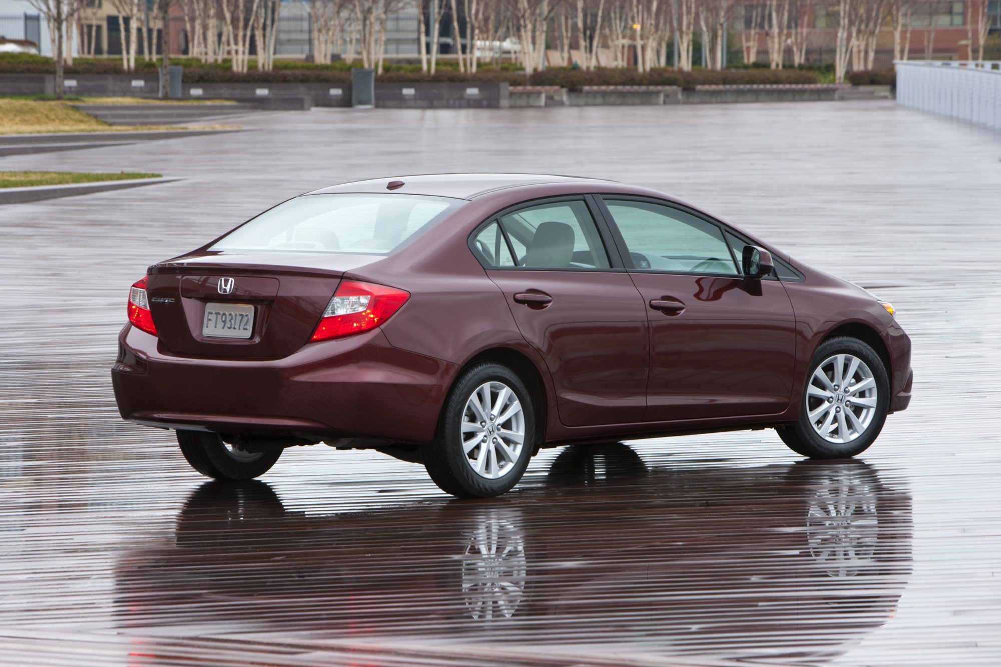 Rear three-quarter view of a dark red 2012 Honda Civic EX-L sedan on a wet plaza