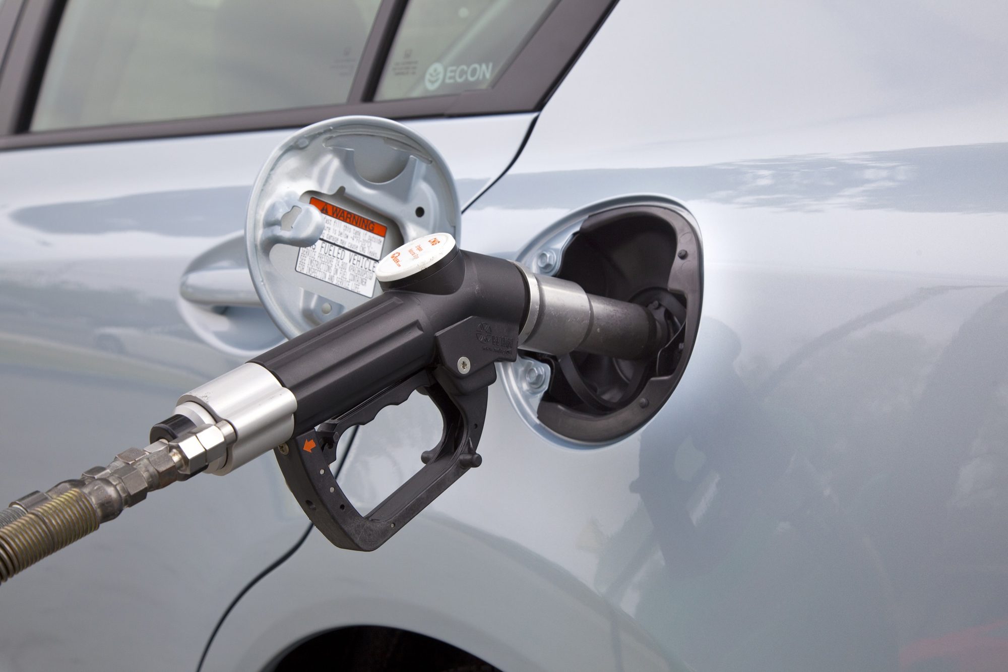 A compressed natural gas nozzle locked onto the fuel receptacle of a 2012 Honda Civic Natural Gas