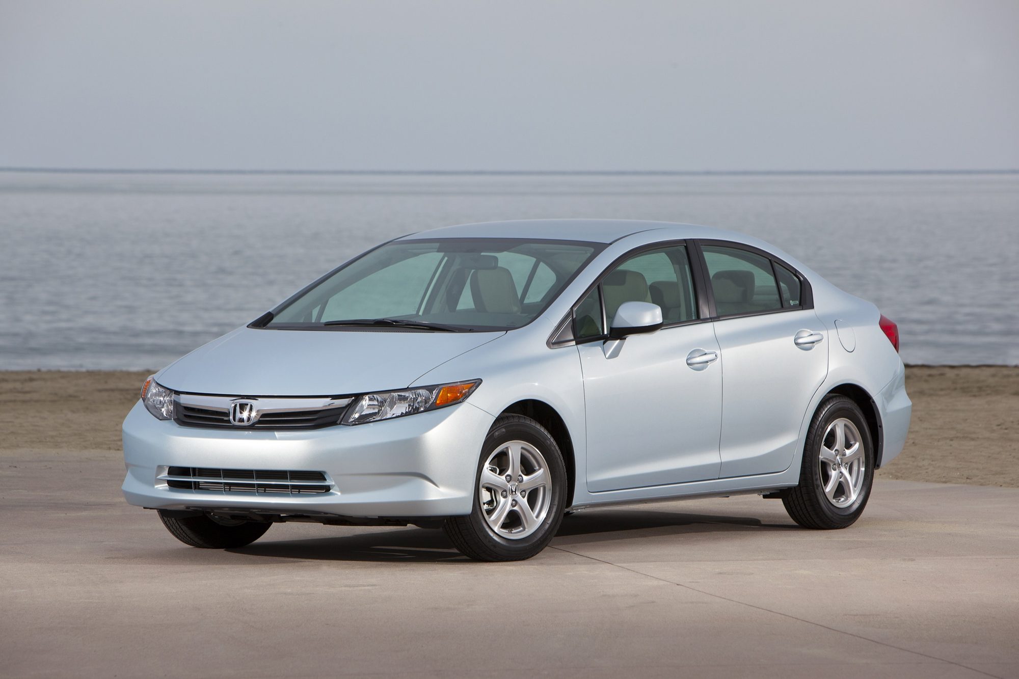 Front three-quarter view of a light blue-silver 2012 Honda Civic Natural Gas sedan parked by the ocean