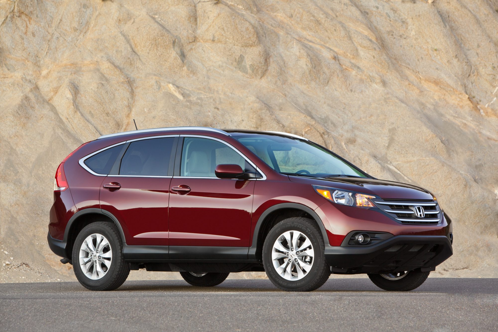 Front three-quarter view of a dark red 2012 Honda CR-V EX-L in front of a sandstone wall