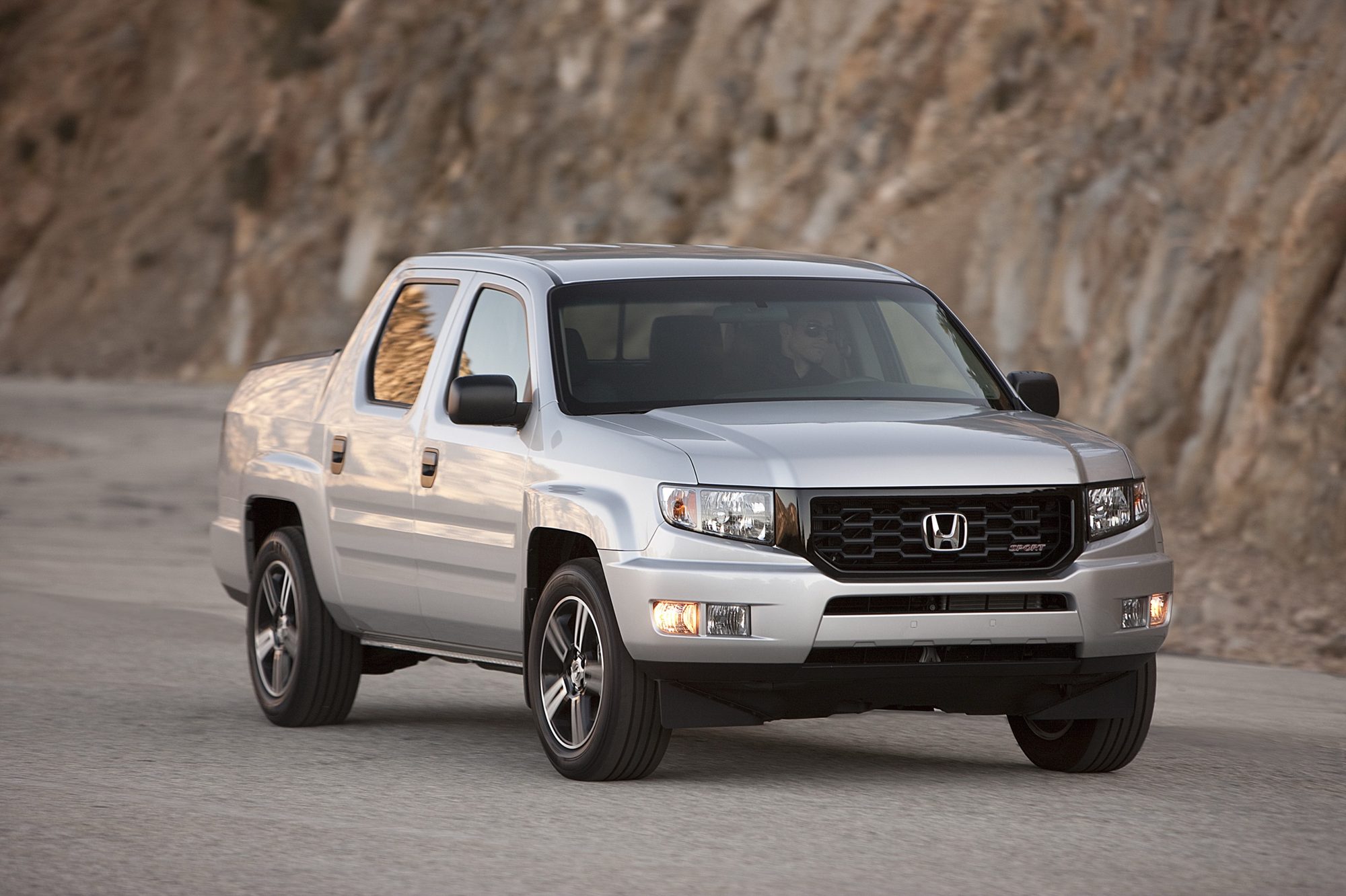 Front three-quarter view of a silver 2012 Honda Ridgeline Sport on a mountain road