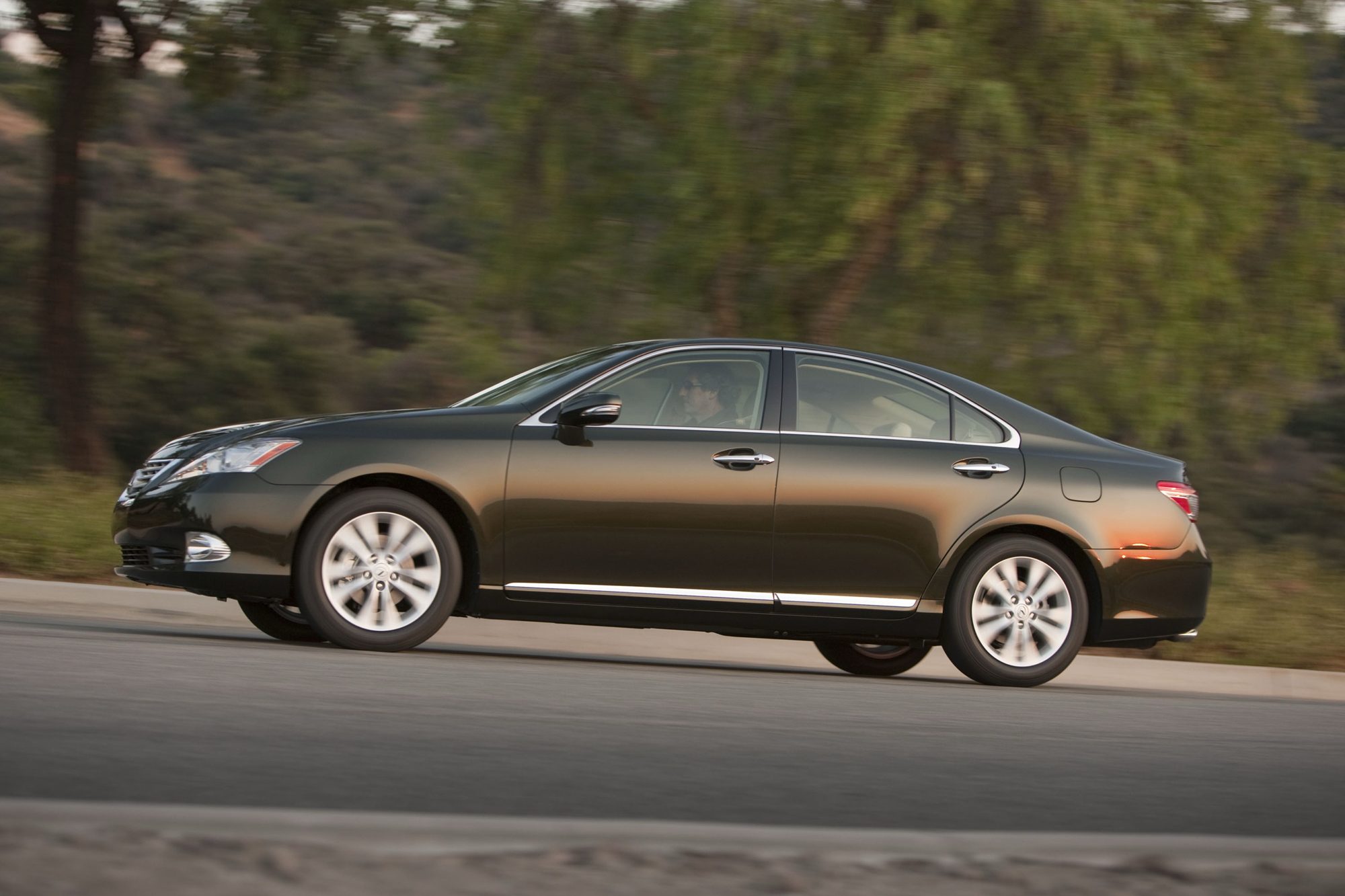 Side profile of a dark green 2012 Lexus ES 350 sedan on the move