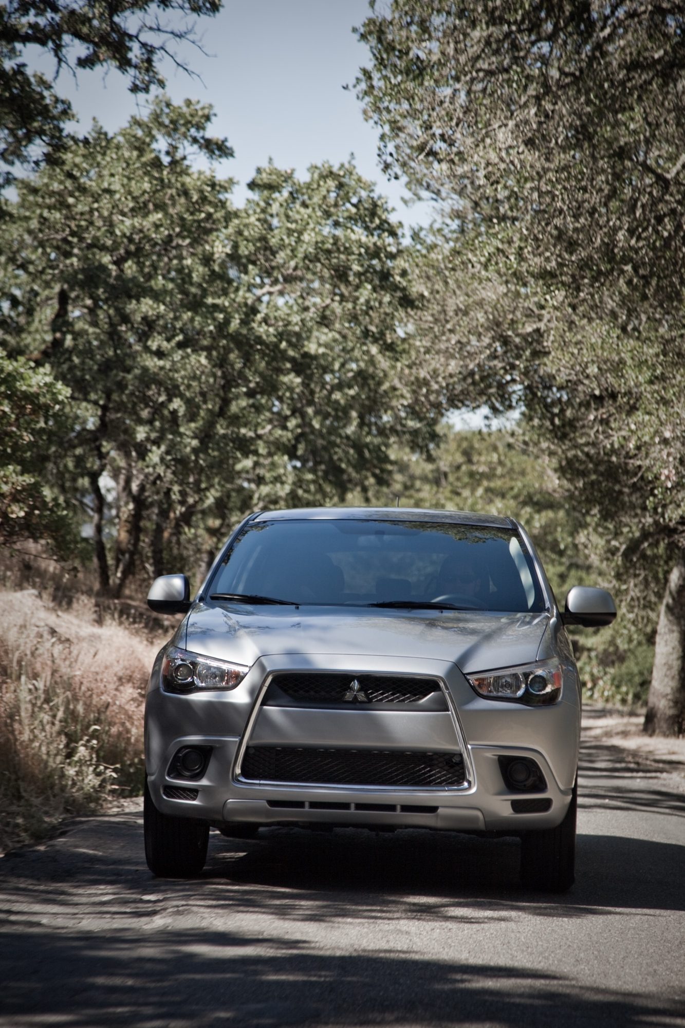 Gray 2012 Mitsubishi Outlander Sport ES driving on a tree-lined road