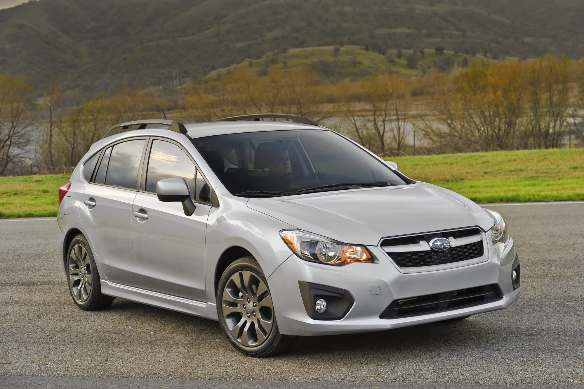 Front three-quarter view of a silver 2012 Subaru Impreza 5-door hatchback by a lake
