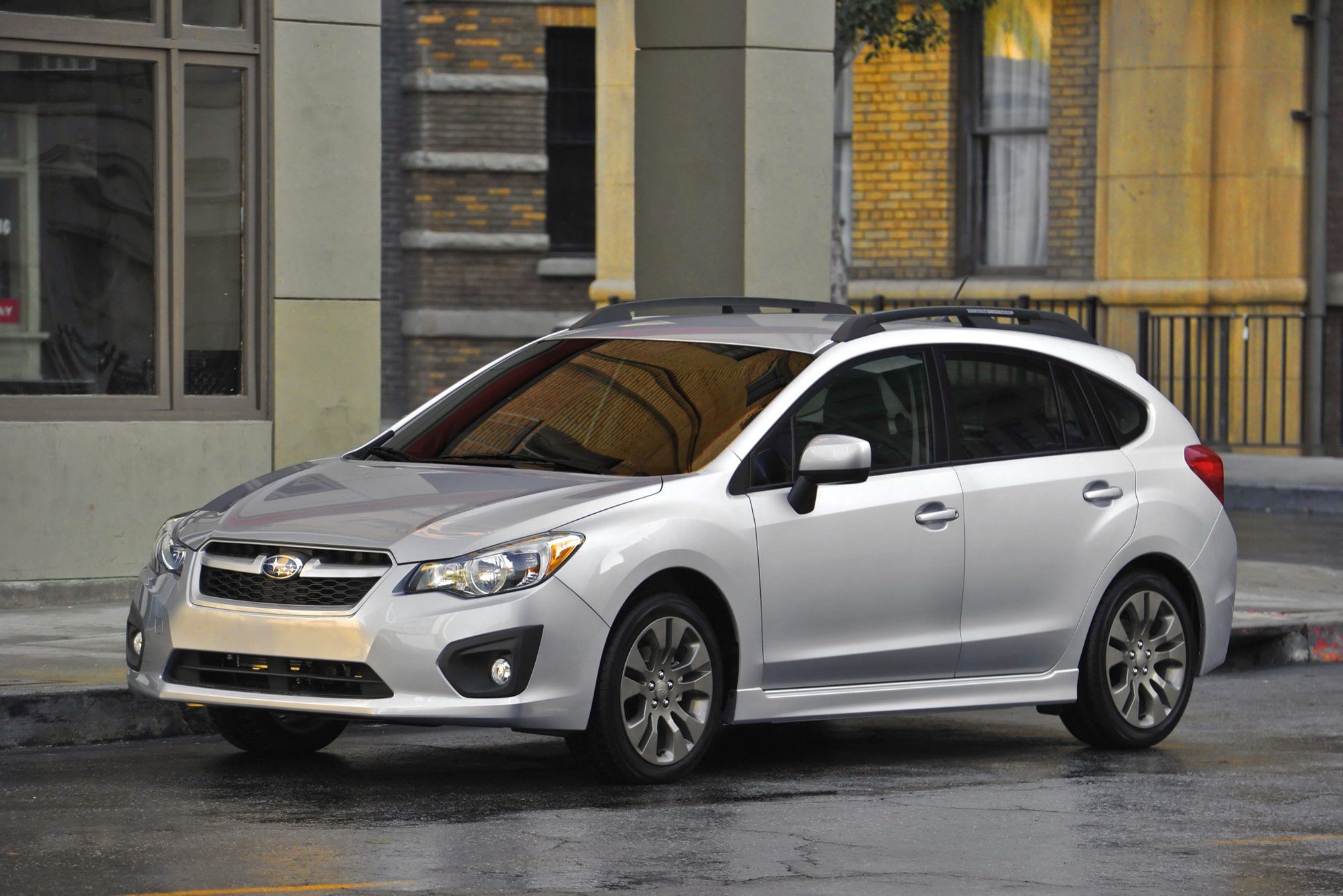 Silver 2012 Subaru Impreza 5-door hatchback parked on a wet city street