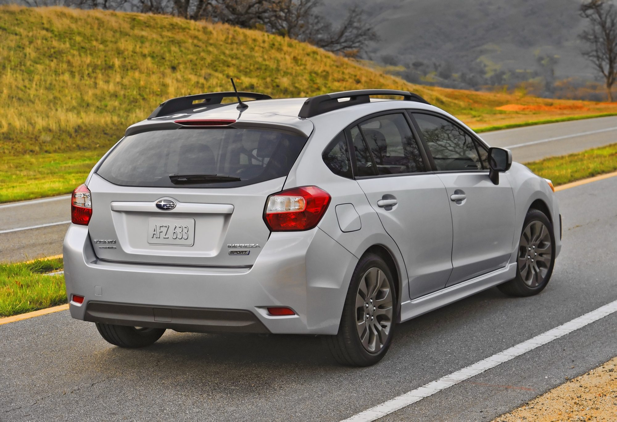 Silver 2012 Subaru Impreza Sport 5-door driving on a country road, seen from the rear