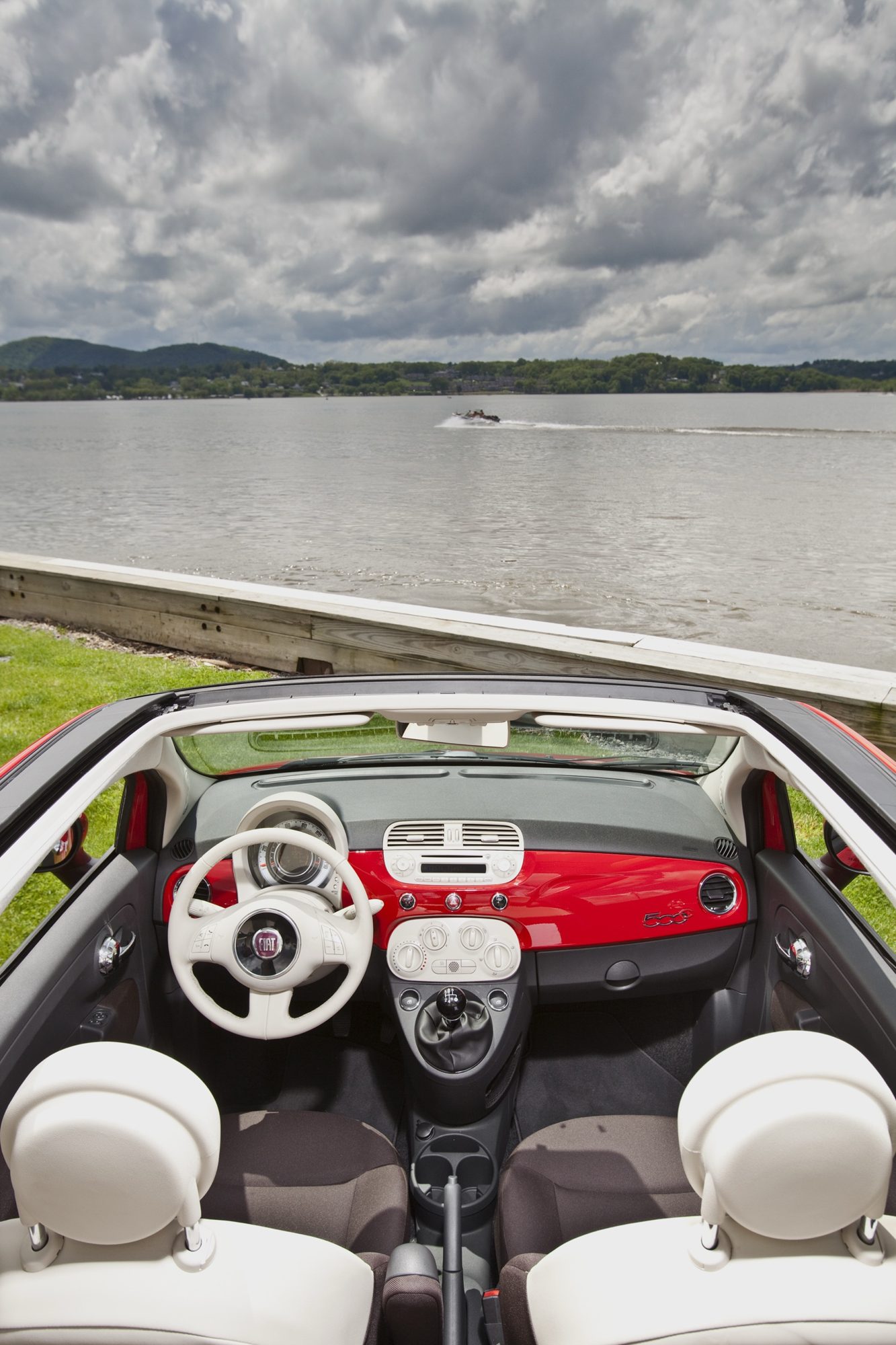 Overhead view of the 2013 Fiat 500c cabin with the top open, showing the red dash panel, ivory steering wheel and manual shifter