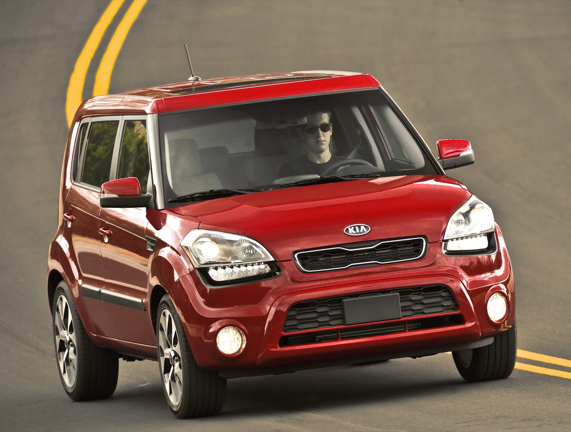 Front three-quarter view of a red 2013 Kia Soul driving on a curving road
