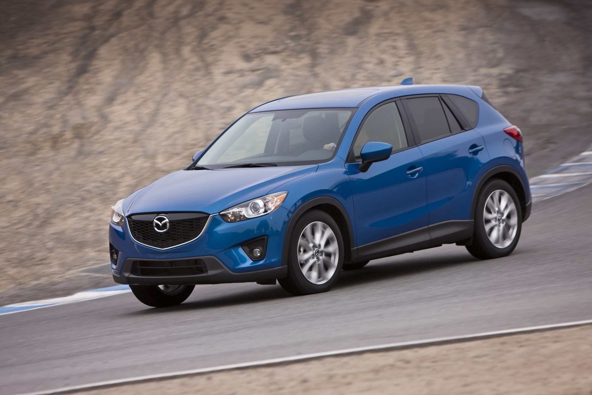 A blue 2013 Mazda CX-5 cornering on a race track