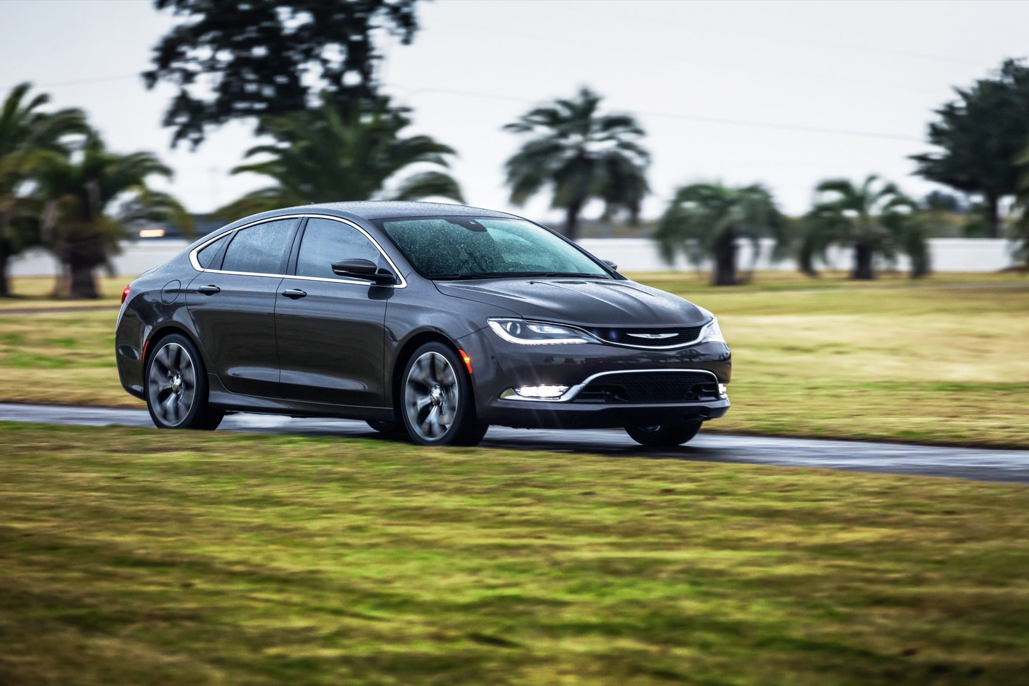 Front three-quarter view of a dark gray 2015 Chrysler 200C on a wet road