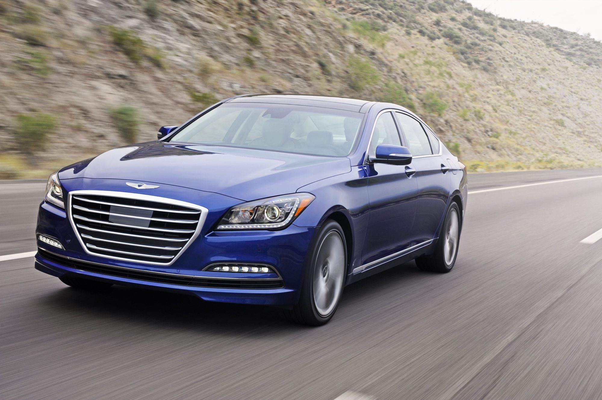 Blue 2015 Hyundai Genesis 5.0 sedan driving on a desert highway