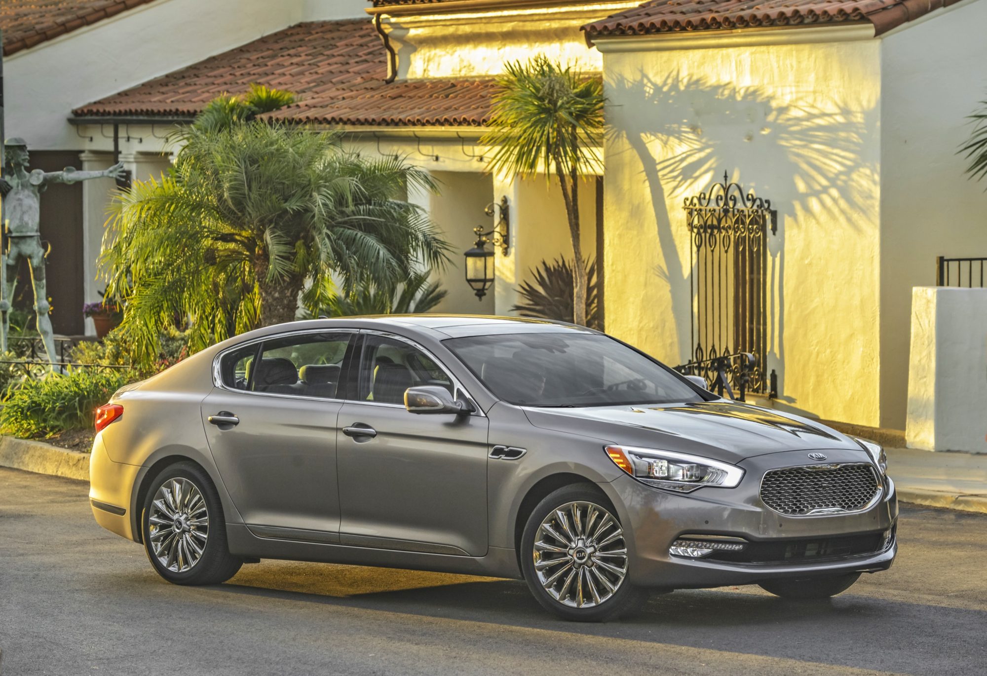 Side view of a gray 2015 Kia K900 V8 parked in front of a Spanish-style building