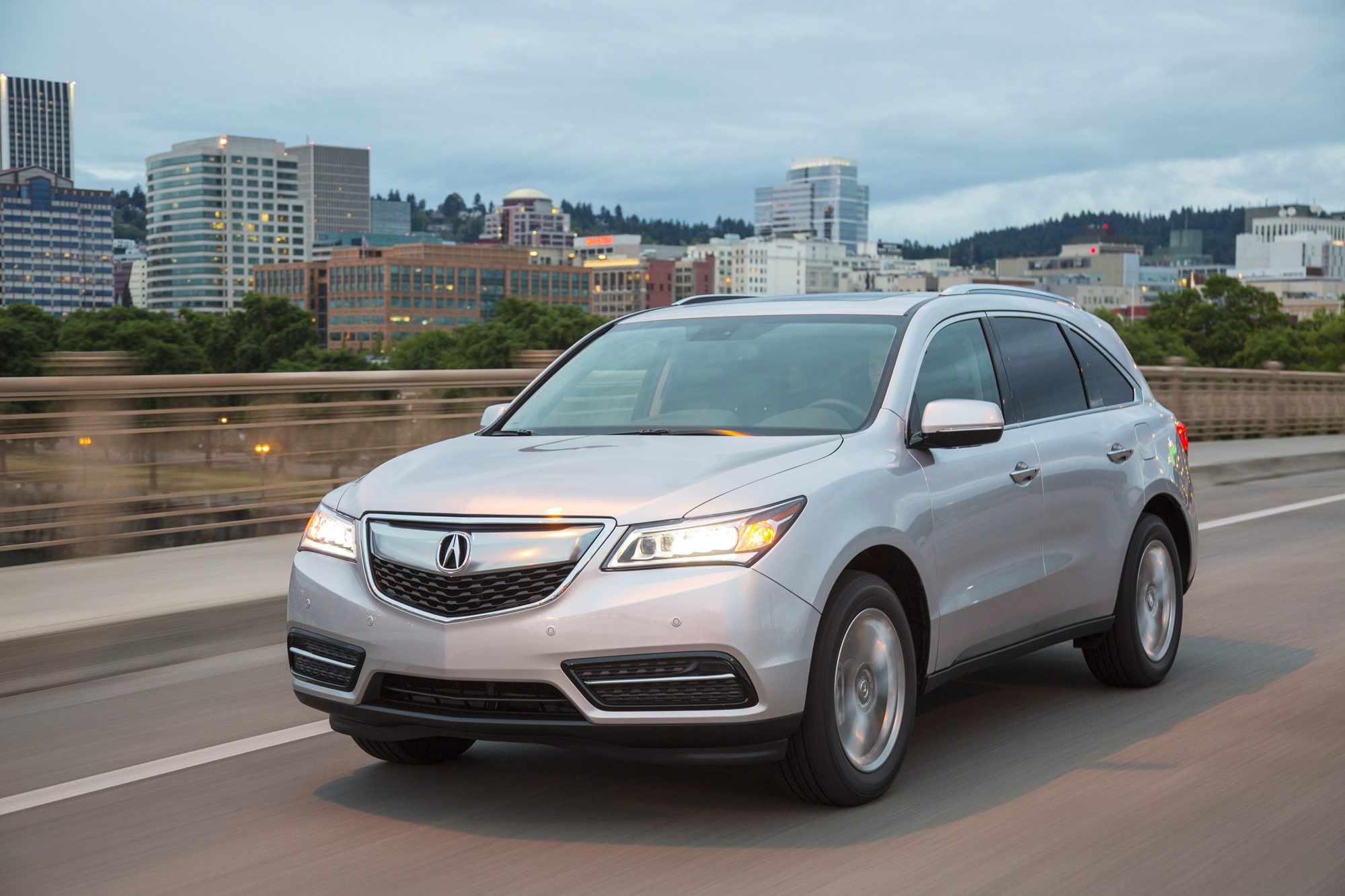 Silver 2016 Acura MDX driving across a city bridge