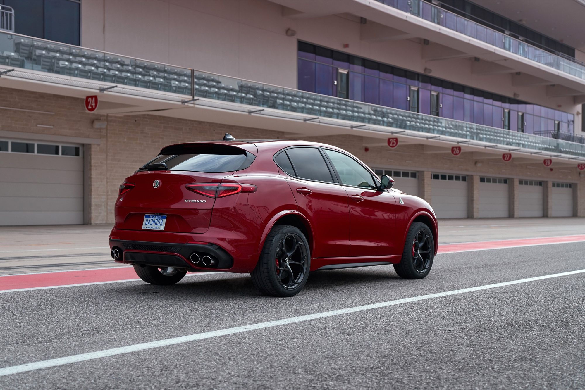 Rear three-quarter view of the 2018 Alfa Romeo Stelvio Quadrifoglio in Rosso Competizione in a pit lane