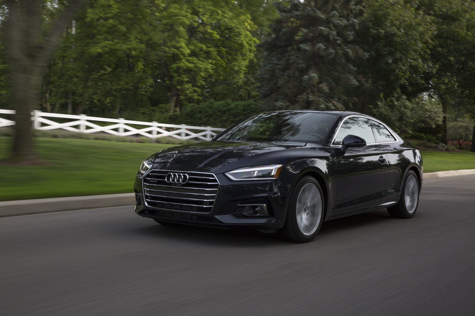 Dark blue 2018 Audi A5 Coupe driving on a tree-lined road