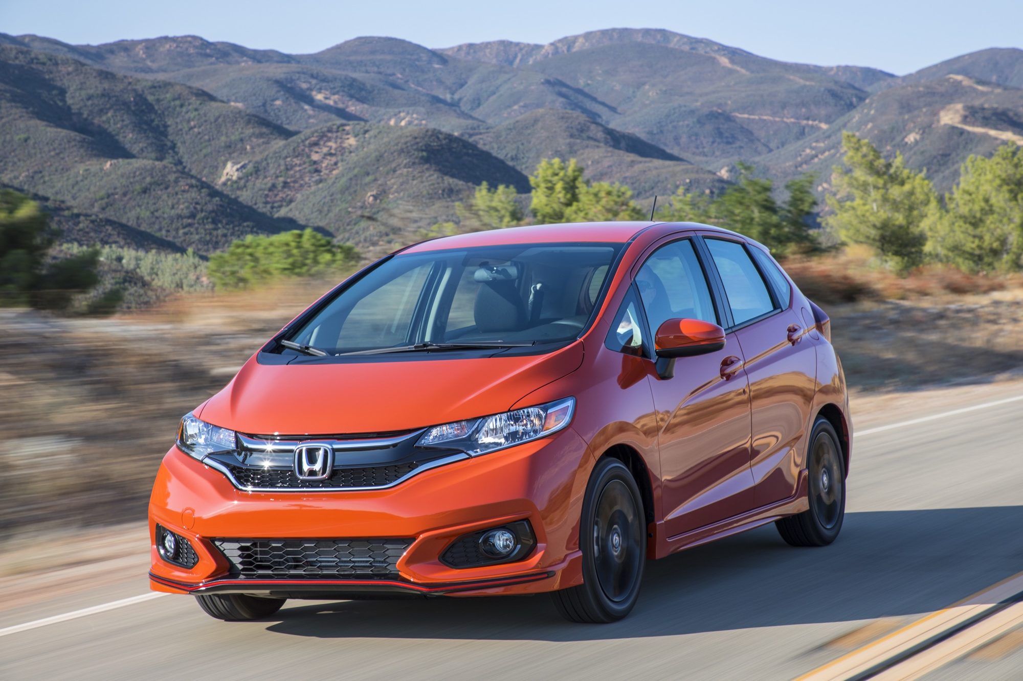 Orange Fury 2018 Honda Fit Sport driving on a mountain road, front three-quarter view