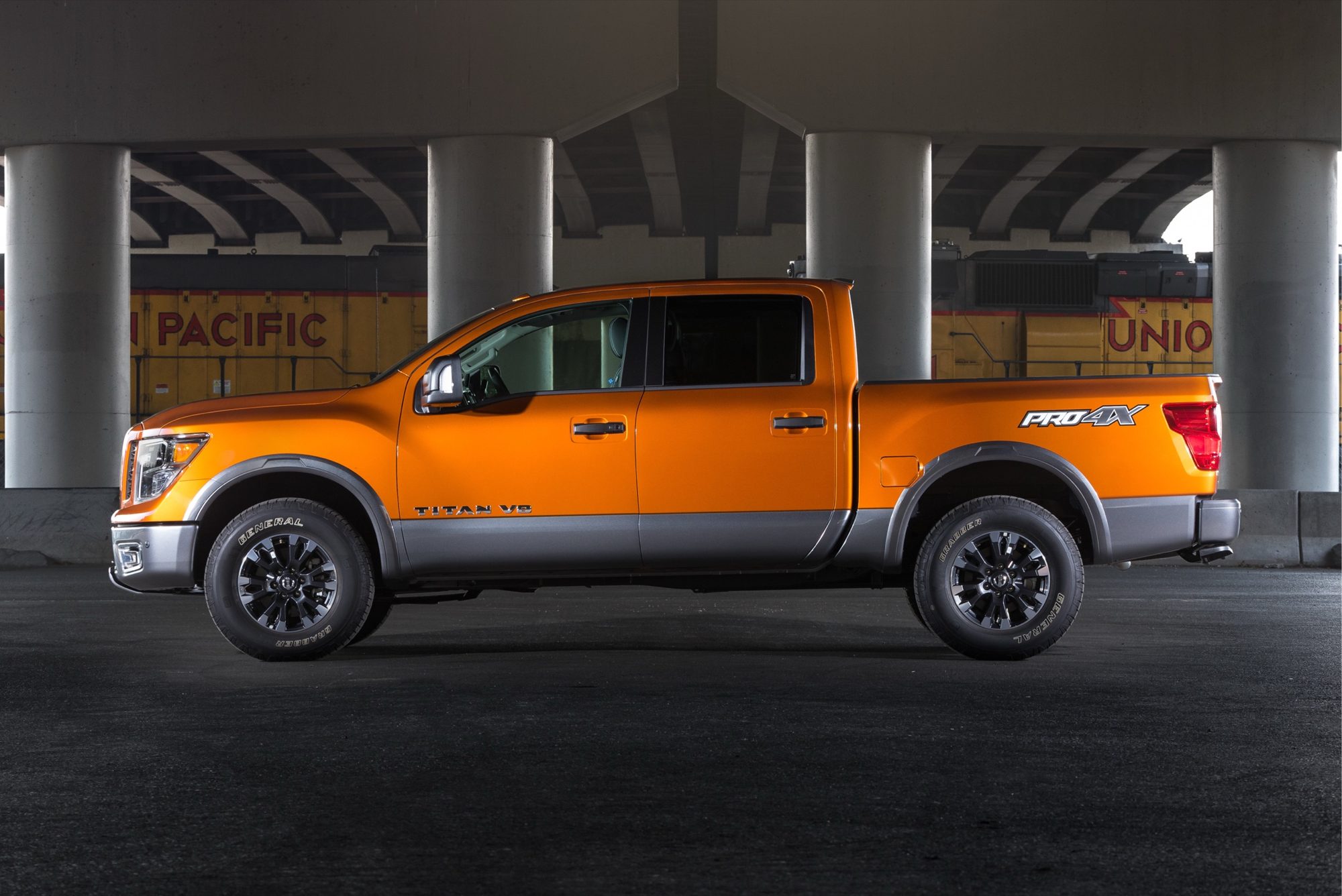 Side profile of an orange 2019 Nissan Titan PRO-4X crew cab under an overpass
