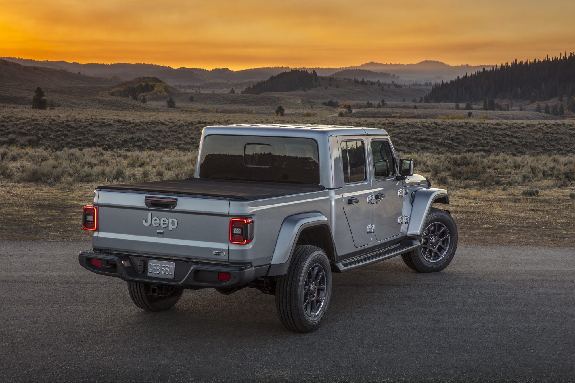 Rear three-quarter view of a silver 2020 Jeep Gladiator Overland with a tonneau cover over the bed