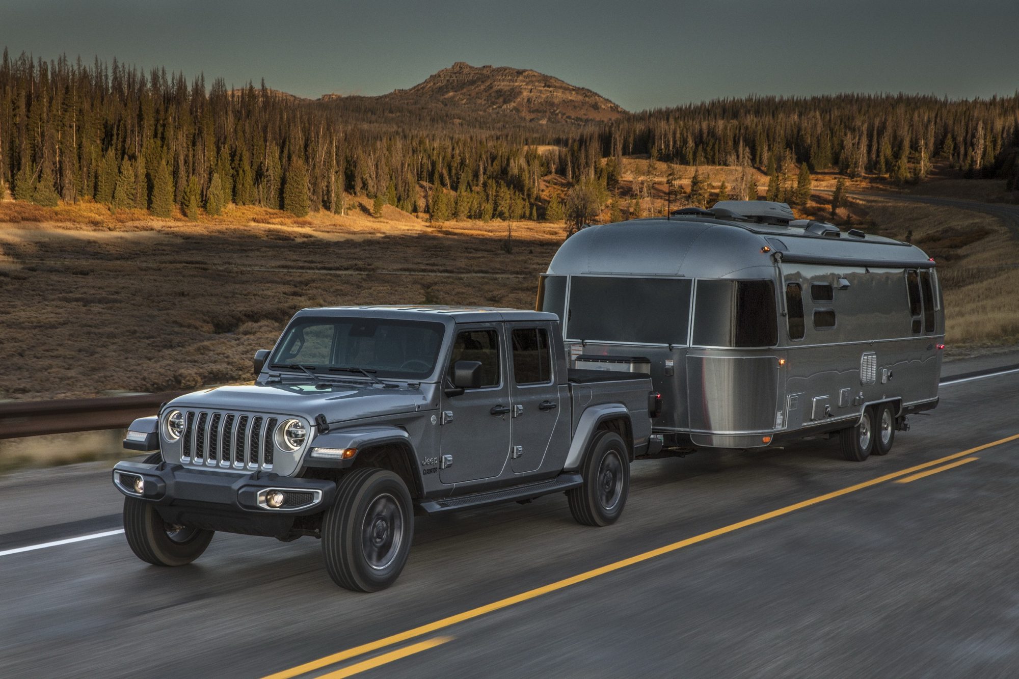 Silver 2020 Jeep Gladiator Overland towing an Airstream travel trailer on a highway