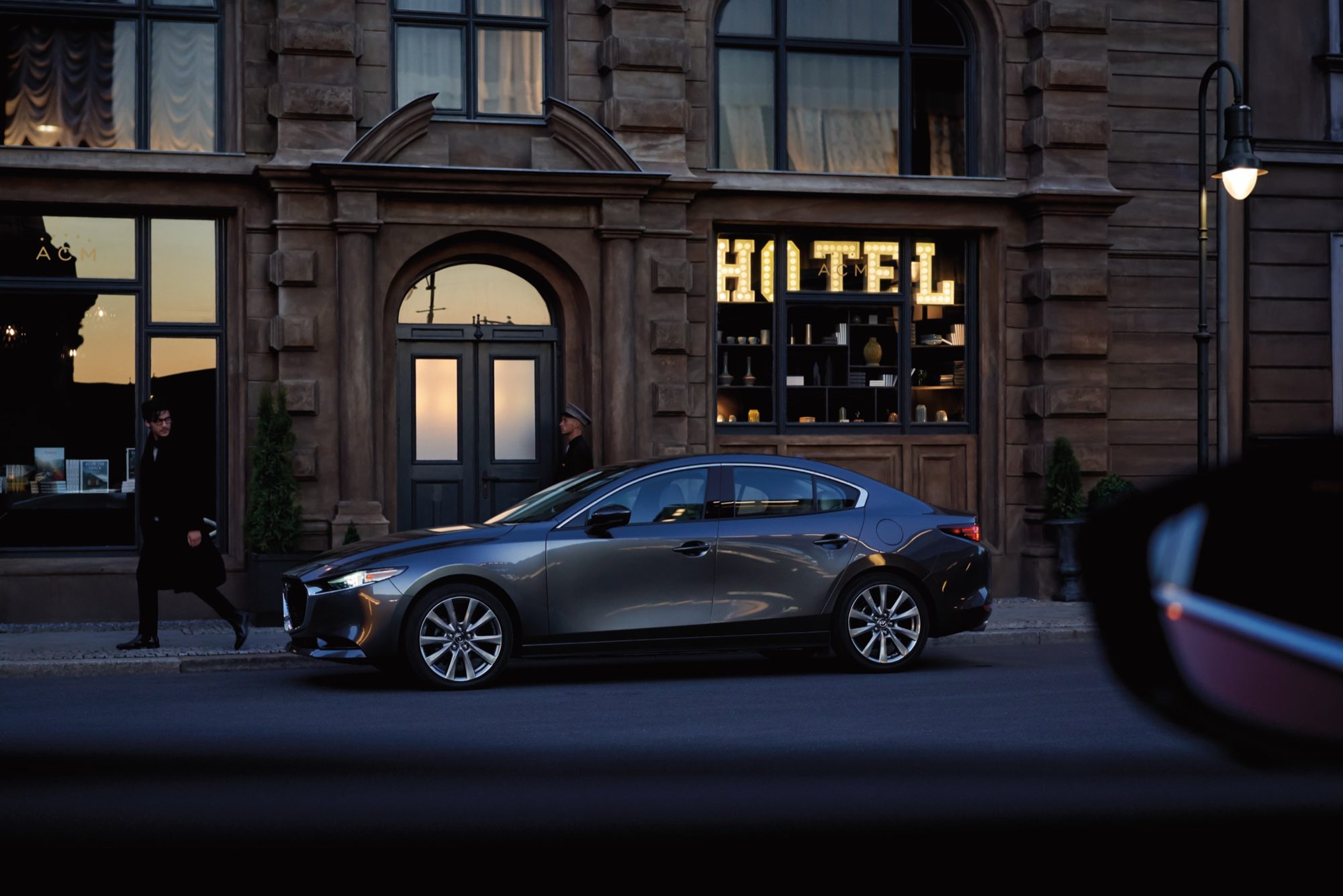 Grey 2020 Mazda3 sedan parked outside a hotel at dusk