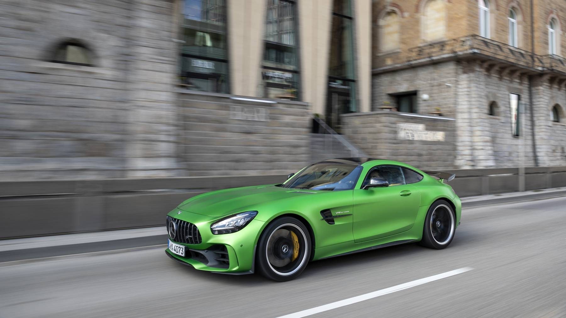 Green 2020 Mercedes-AMG GT R coupe driving past a stone building