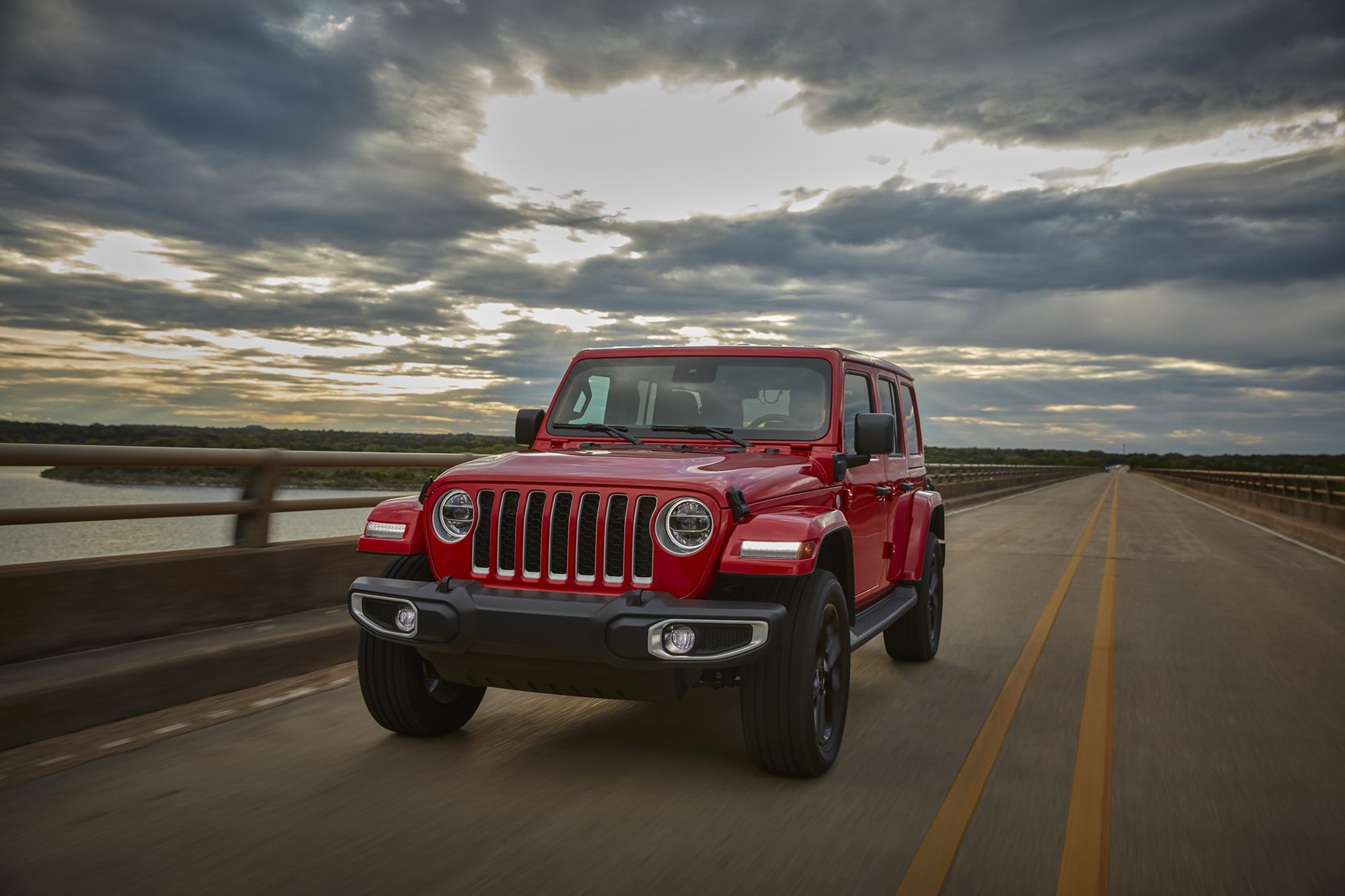 Red 2021 Jeep Wrangler Sahara 4xe on a bridge under a cloudy sky