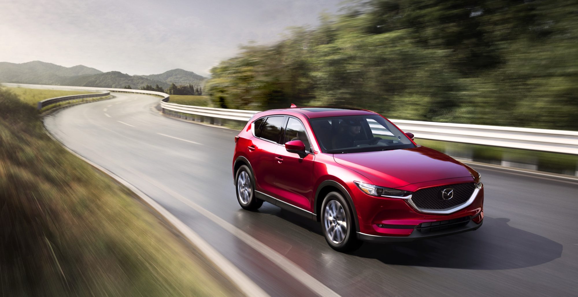 Red 2021 Mazda CX-5 driving on a curving highway