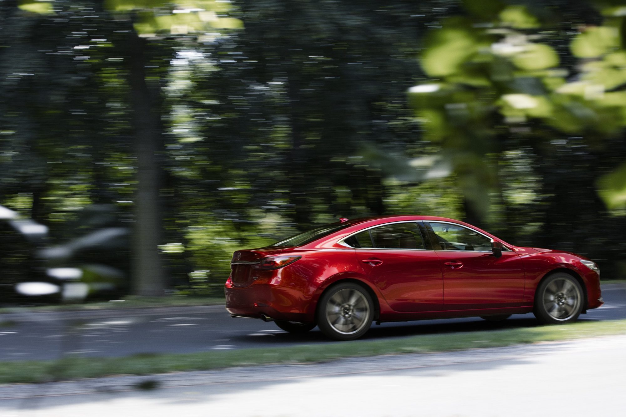 Red 2021 Mazda6 sedan driving on a tree-lined road