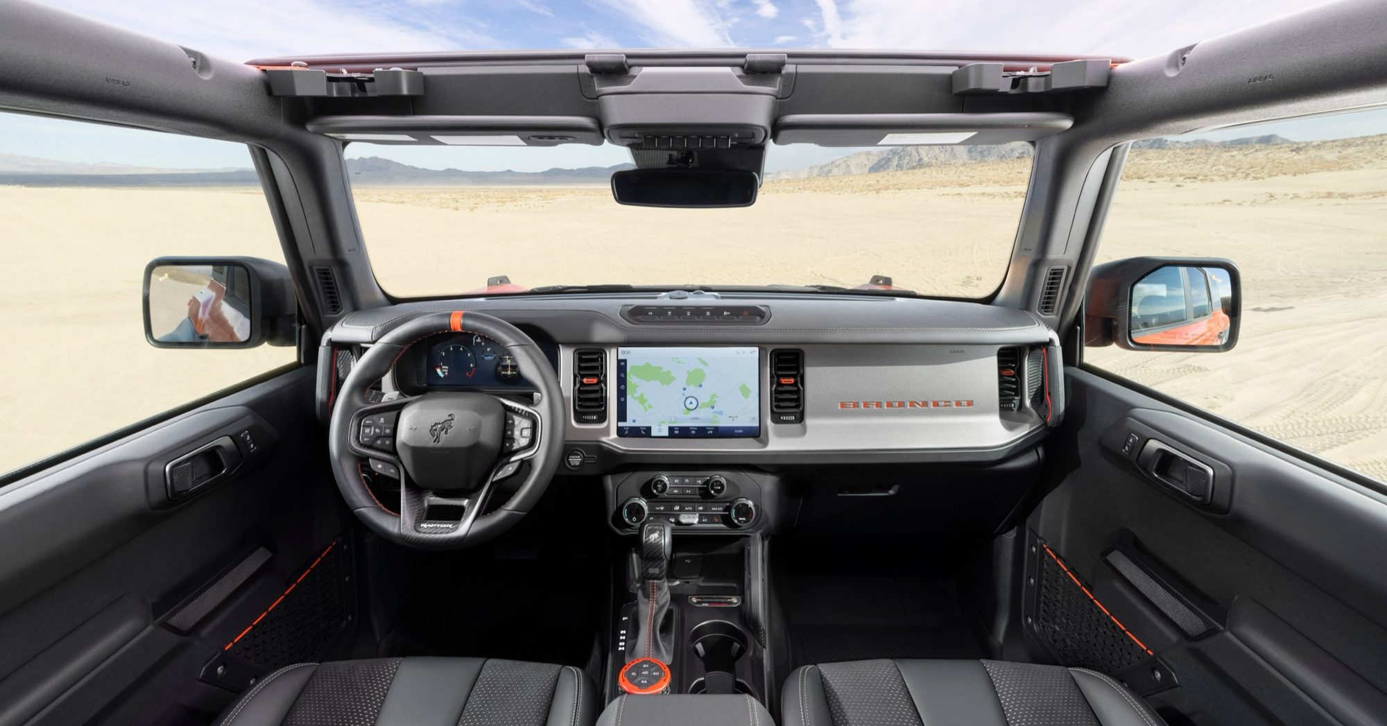 Dashboard of the 2022 Ford Bronco Raptor with 12-inch touchscreen, Raptor steering wheel and orange accents