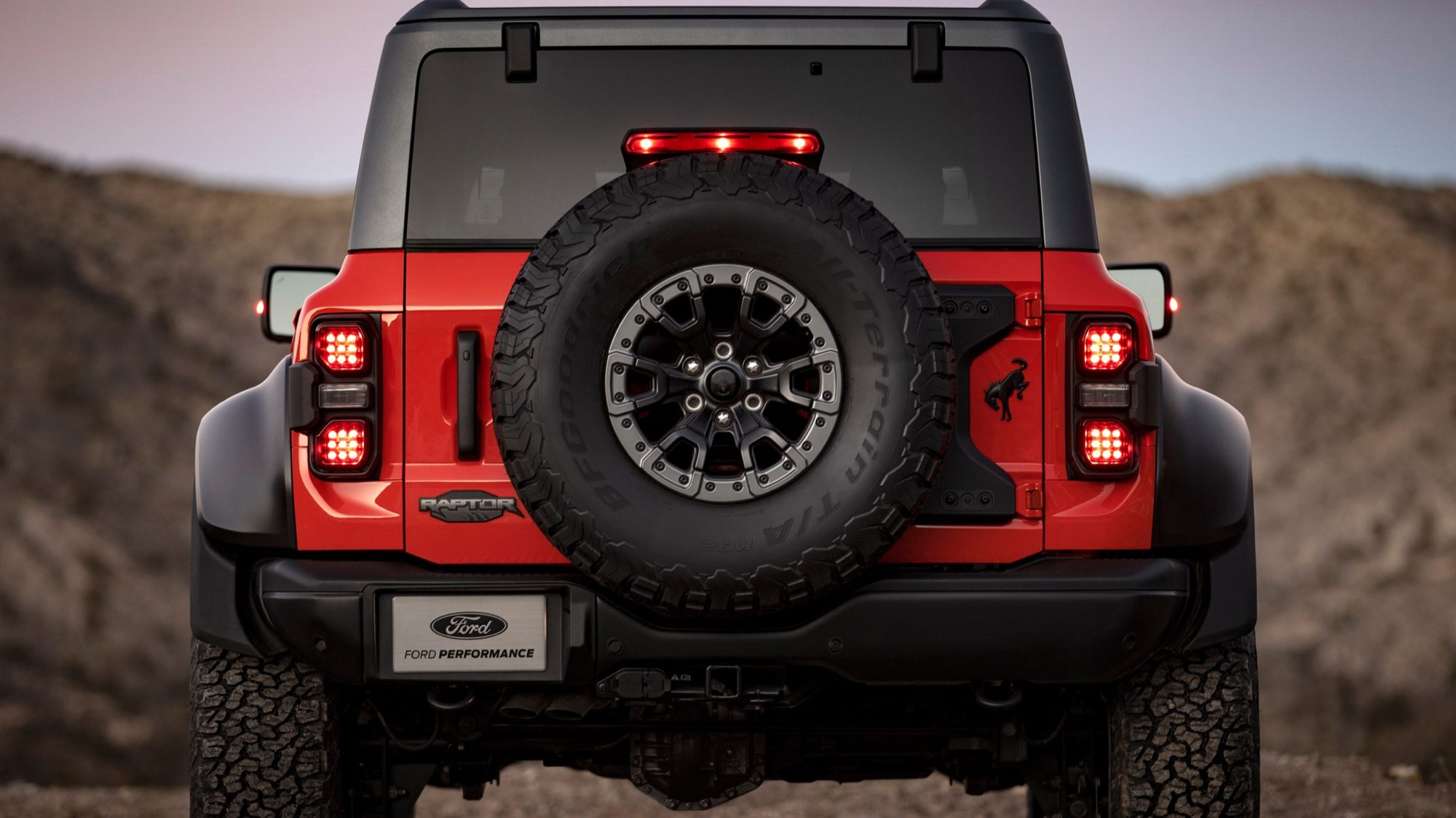 Rear of a Code Orange 2022 Ford Bronco Raptor with its full-size spare tire mounted on the tailgate