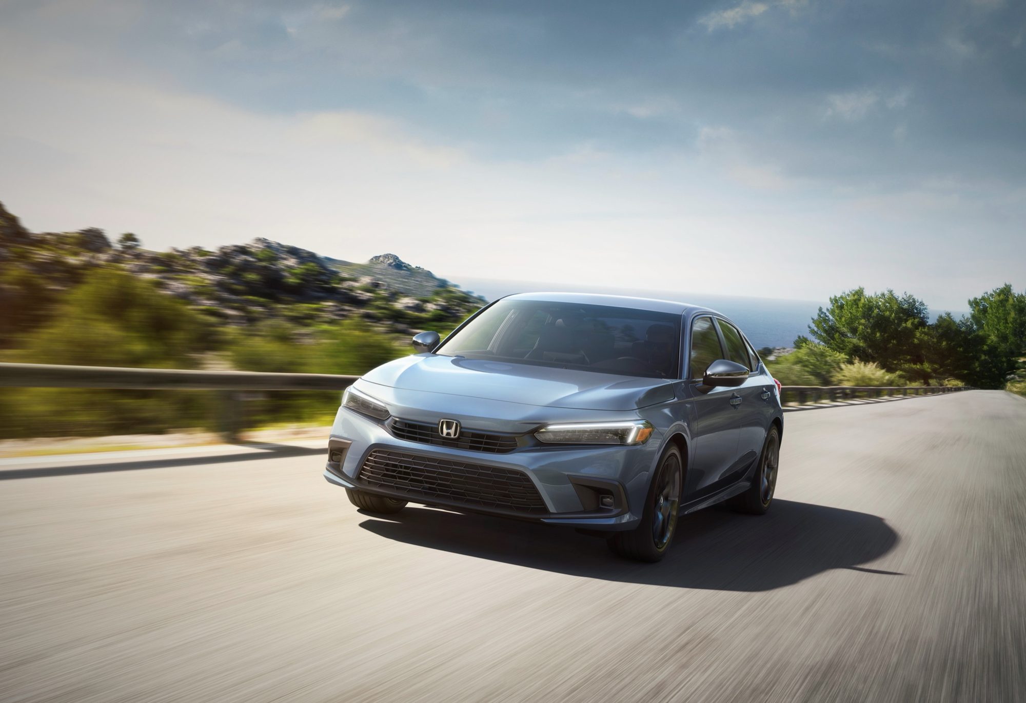 Gray 2022 Honda Civic Sport sedan driving on a coastal road